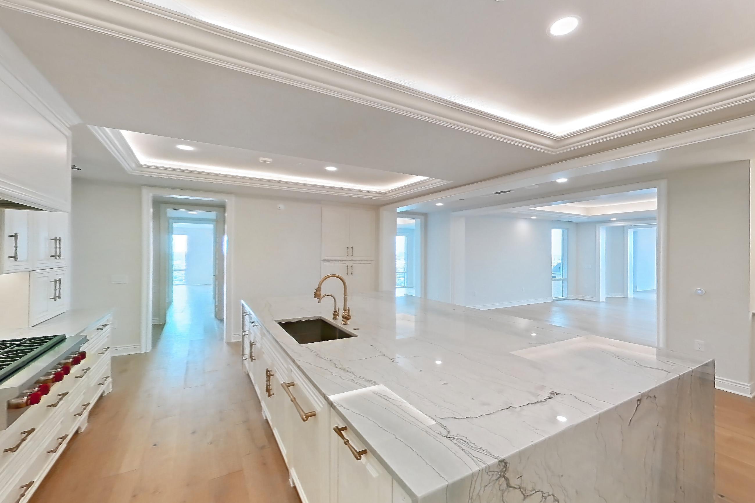 Kitchen space with cooktop, gas cooktop, kitchen island, light stone countertops, light wood-finish flooring, stainless steel appliances, and wood-finish flooring, Apartment 1807 at The Langley