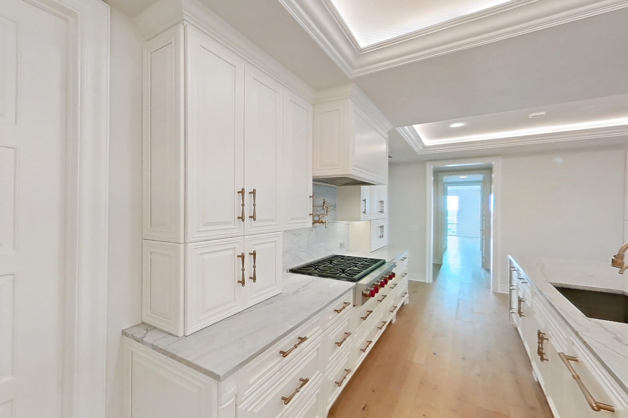 Kitchen space with cooktop, gas cooktop, kitchen island, light stone countertops, light wood-finish flooring, stainless steel appliances, and wood-finish flooring, Apartment 1807 at The Langley