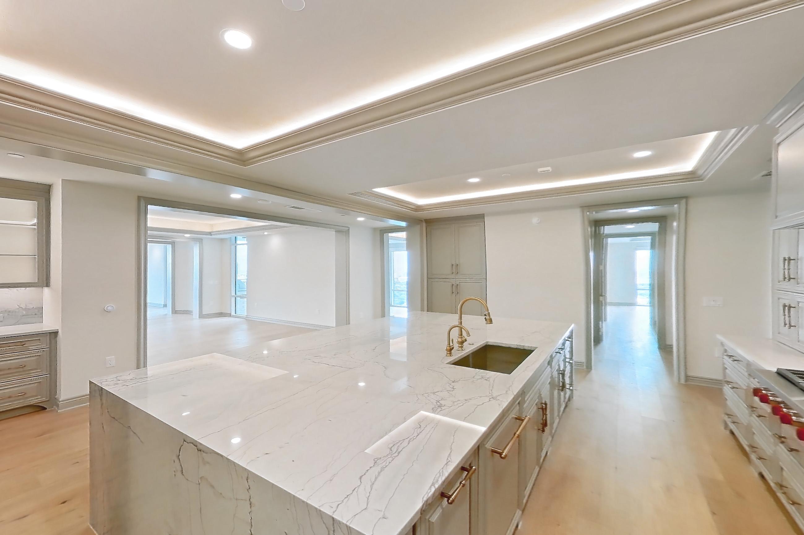 Kitchen space with cooktop, gas cooktop, kitchen island, light stone countertops, light wood-finish flooring, stainless steel appliances, and wood-finish flooring, Apartment 1902 at The Langley