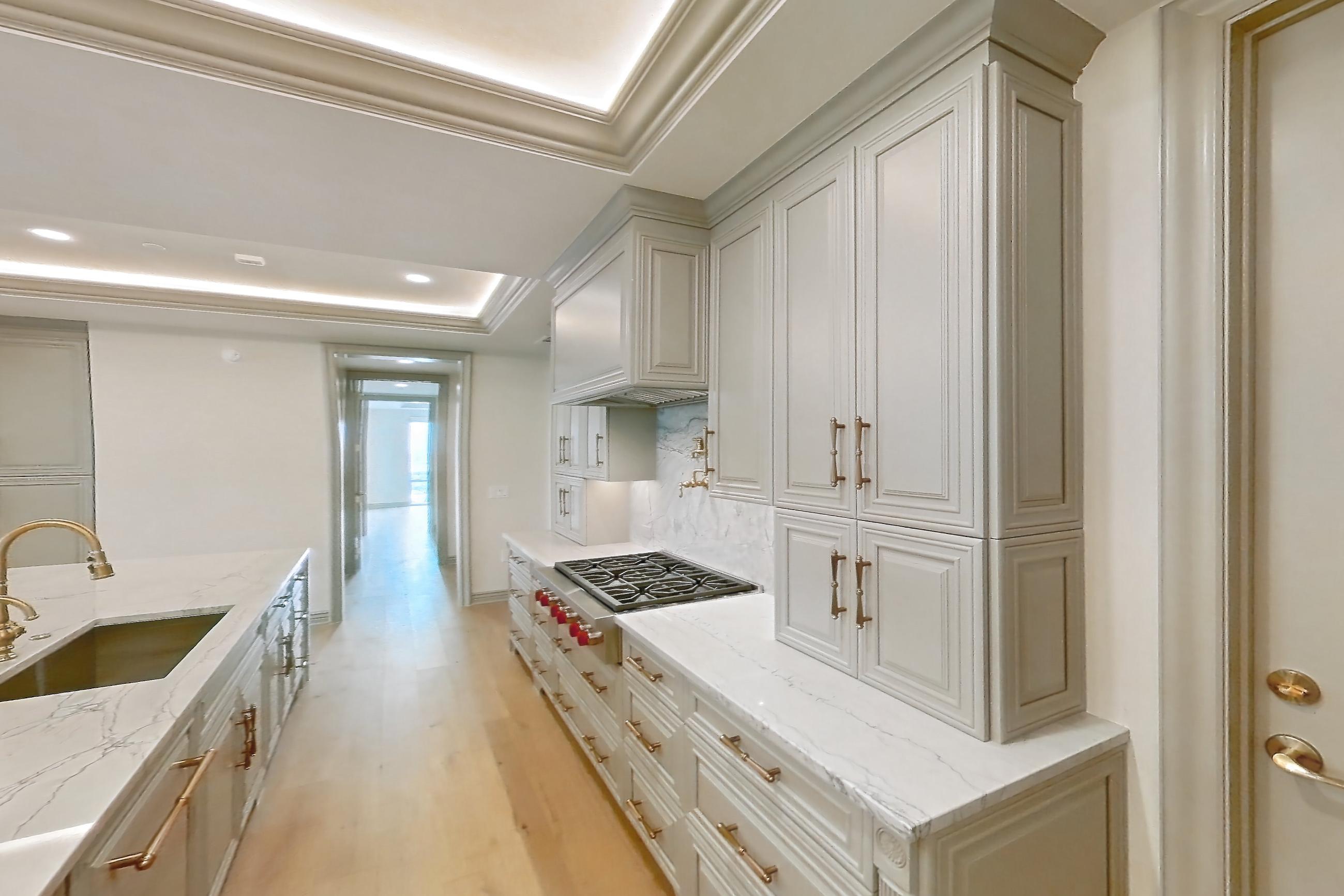 Kitchen space with cooktop, gas cooktop, kitchen island, light stone countertops, light wood-finish flooring, stainless steel appliances, and wood-finish flooring, Apartment 1902 at The Langley