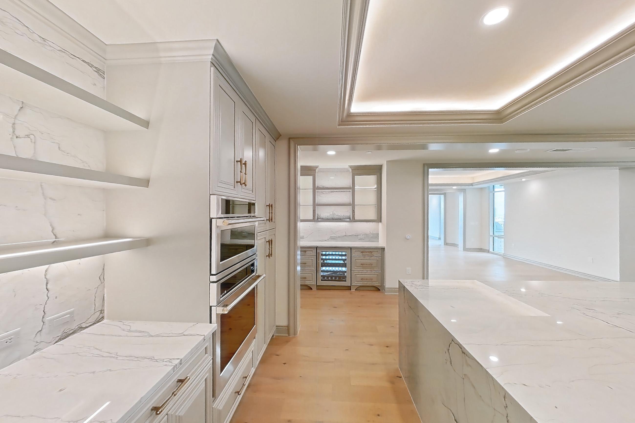 Kitchen space with cooktop, gas cooktop, kitchen island, light stone countertops, light wood-finish flooring, stainless steel appliances, and wood-finish flooring, Apartment 1902 at The Langley