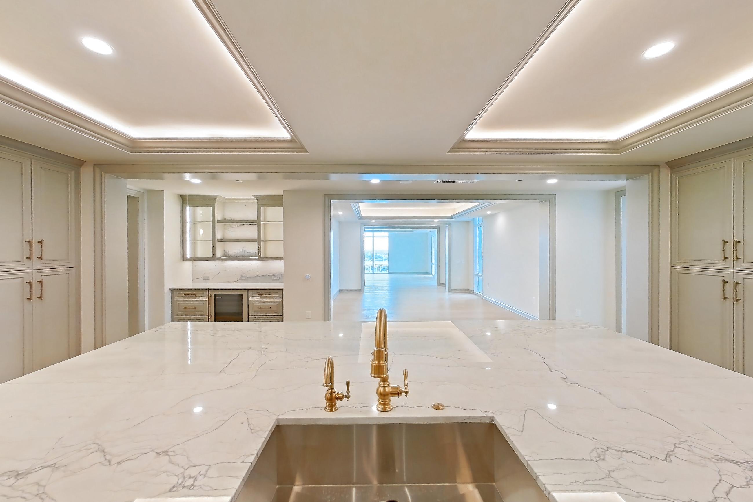 Kitchen with gas range, kitchen island, light stone countertops, light wood-finish flooring, oven/range, and stainless steel appliances, Apartment 1902 at The Langley