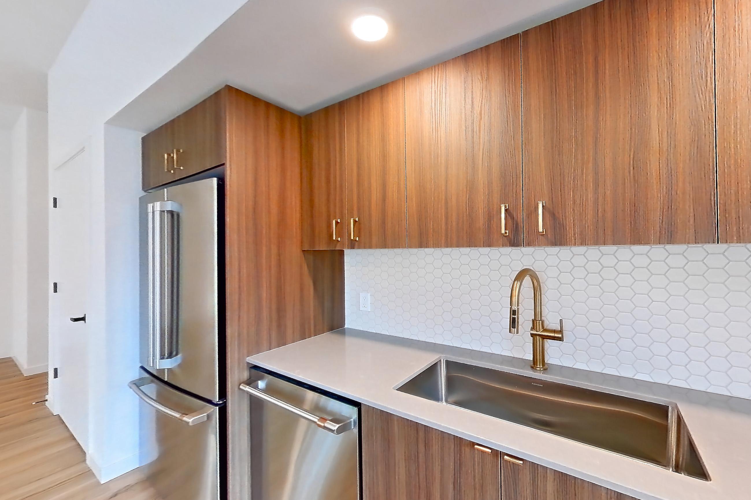 Kitchen with dishwasher, electric range, light countertops, light stone countertops, light wood-finish flooring, microwave, mini-split AC, oven/range, refrigerator, and stainless steel appliances, Apartment 107 at Montage Tigard