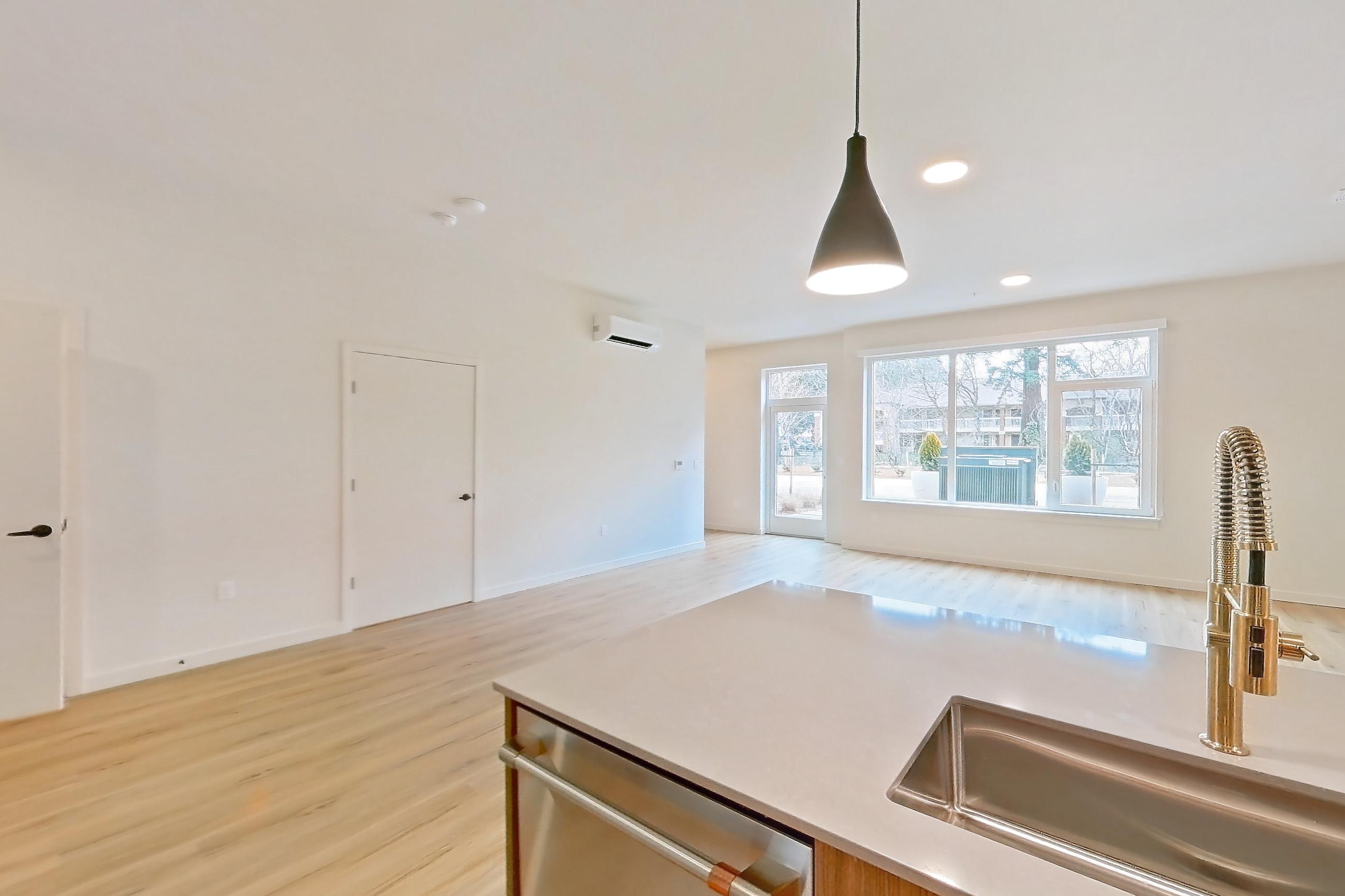 Kitchen with dishwasher, electric range, light countertops, light stone countertops, light wood-finish flooring, microwave, mini-split AC, oven/range, refrigerator, and stainless steel appliances, Apartment 106 at Montage Tigard
