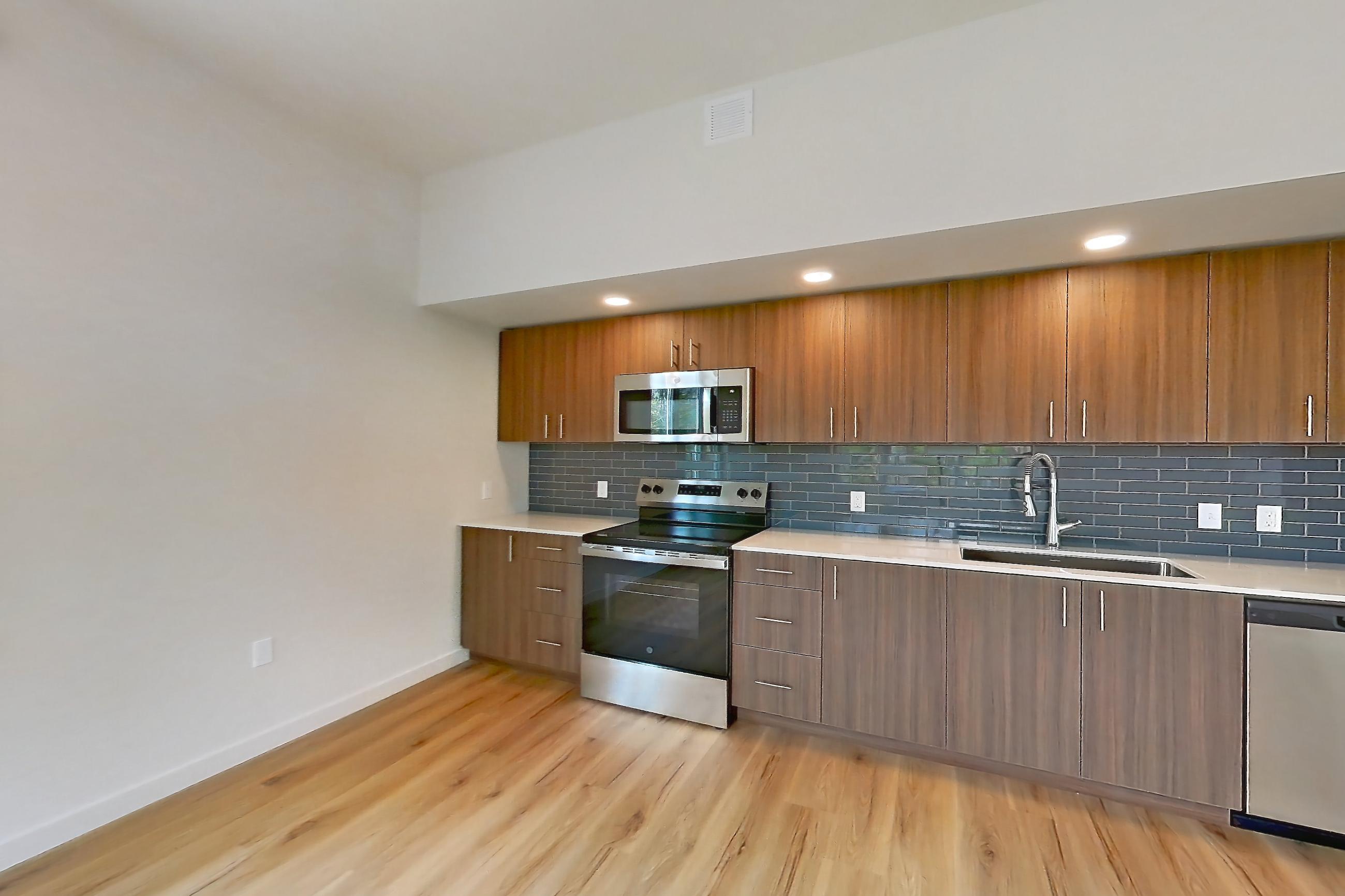 Living room with air conditioning, electric range, light countertops, light wood-finish flooring, microwave, oven/range, and stainless steel appliances, Apartment 344 at Montage Tigard