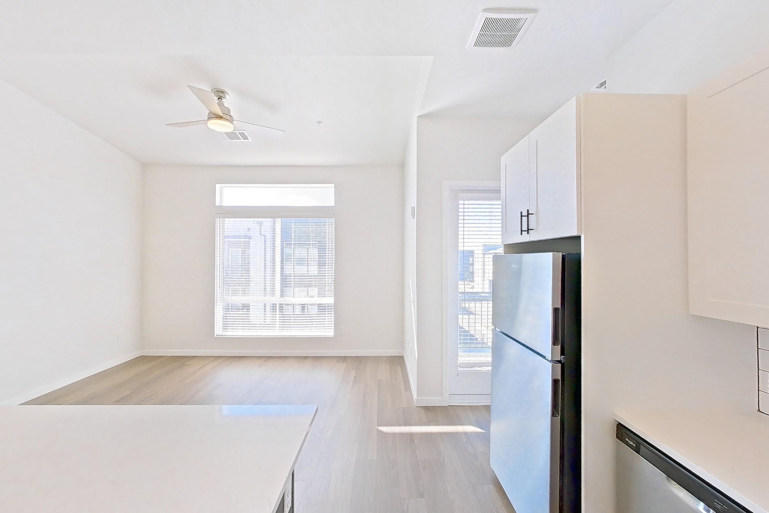 Kitchen with dishwasher, electric range, light countertops, light stone countertops, light wood-finish flooring, microwave, oven/range, and stainless steel appliances, Apartment 10-307 at Marlon at Central Park
