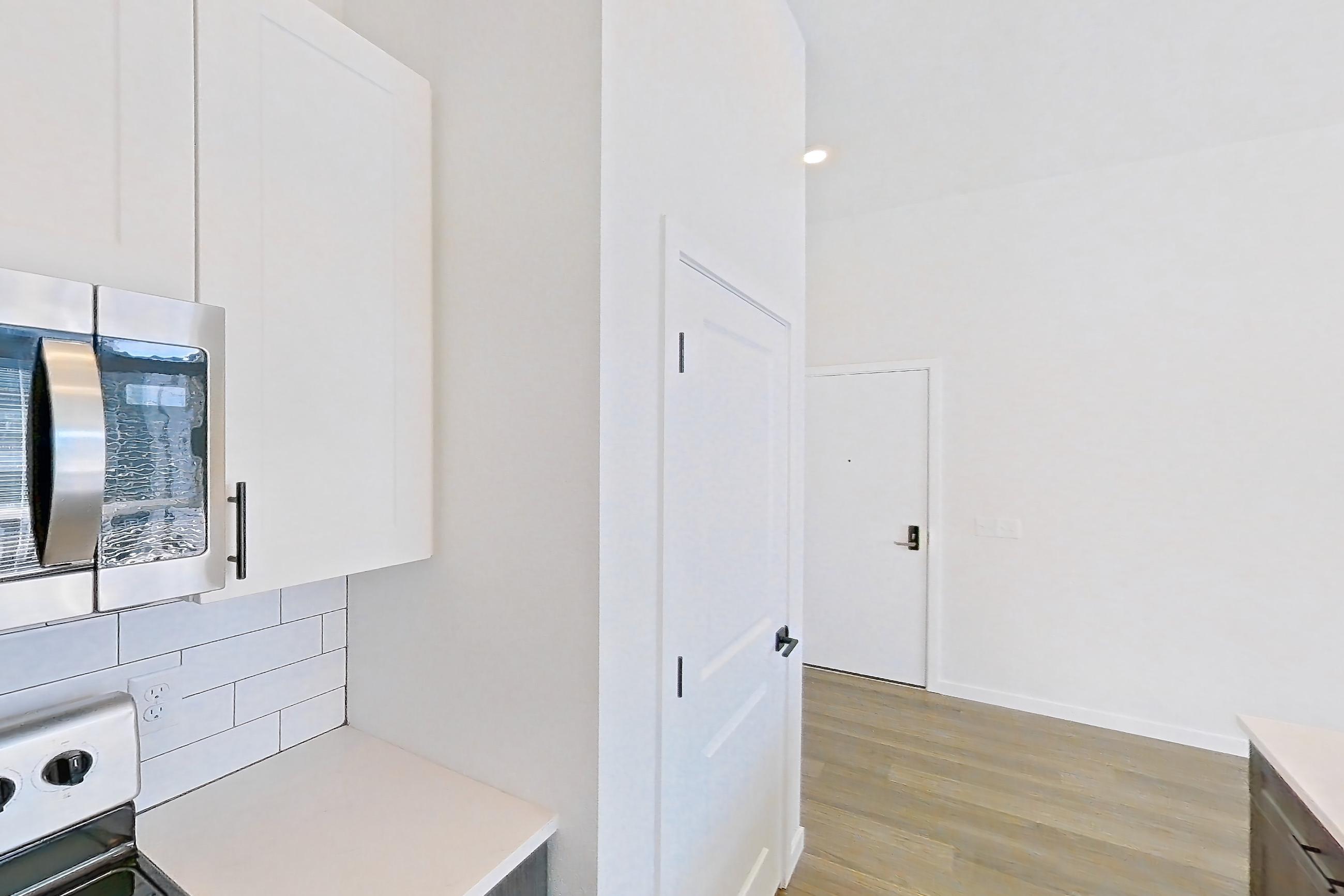 Kitchen with dishwasher, electric range, light countertops, light stone countertops, light wood-finish flooring, microwave, oven/range, and stainless steel appliances, Apartment 10-307 at Marlon at Central Park
