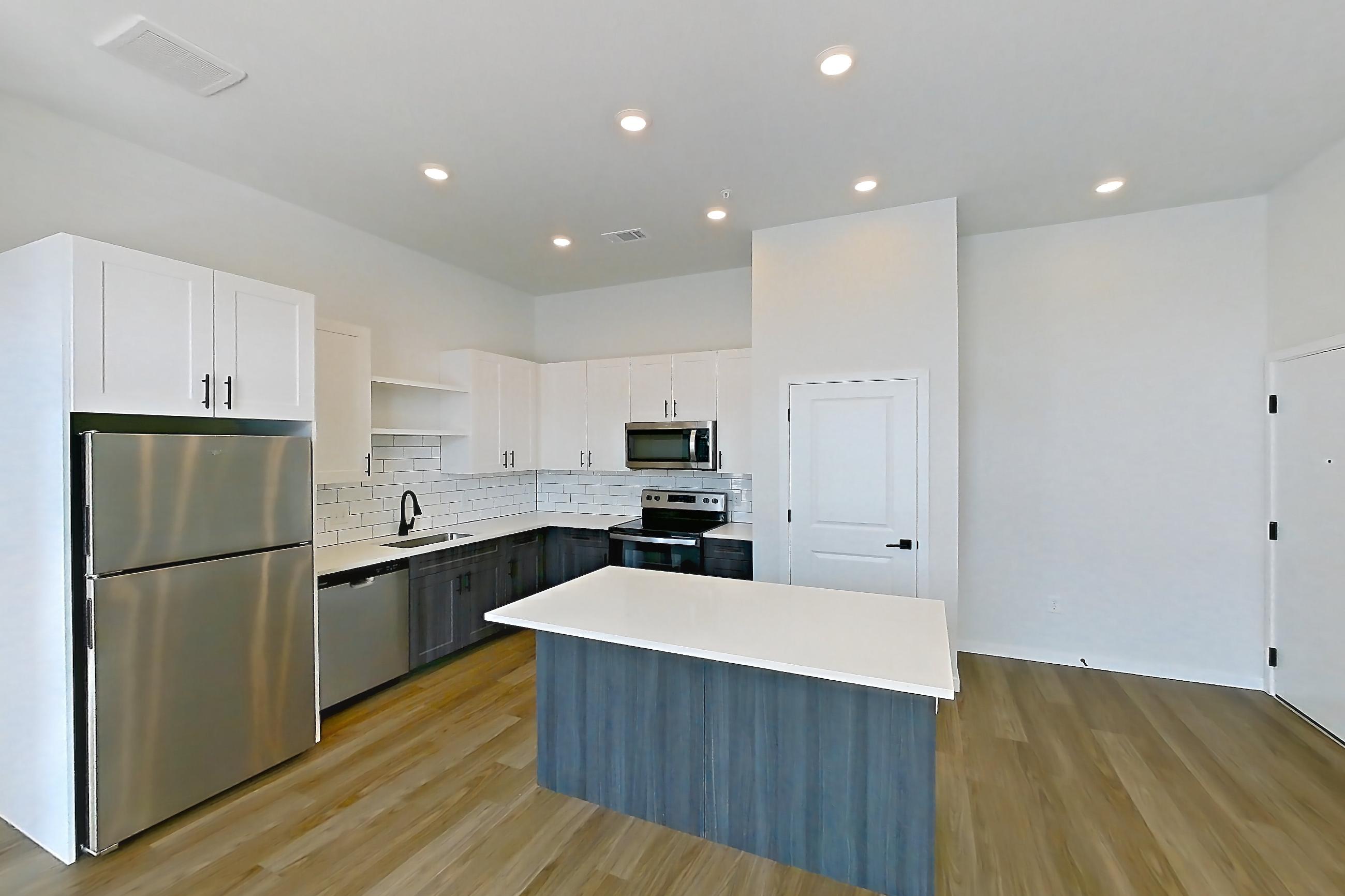 Living space with dark wood-finish flooring, dishwasher, electric range, light countertops, oven/range, refrigerator, and stainless steel appliances, Apartment 10-307 at Marlon at Central Park