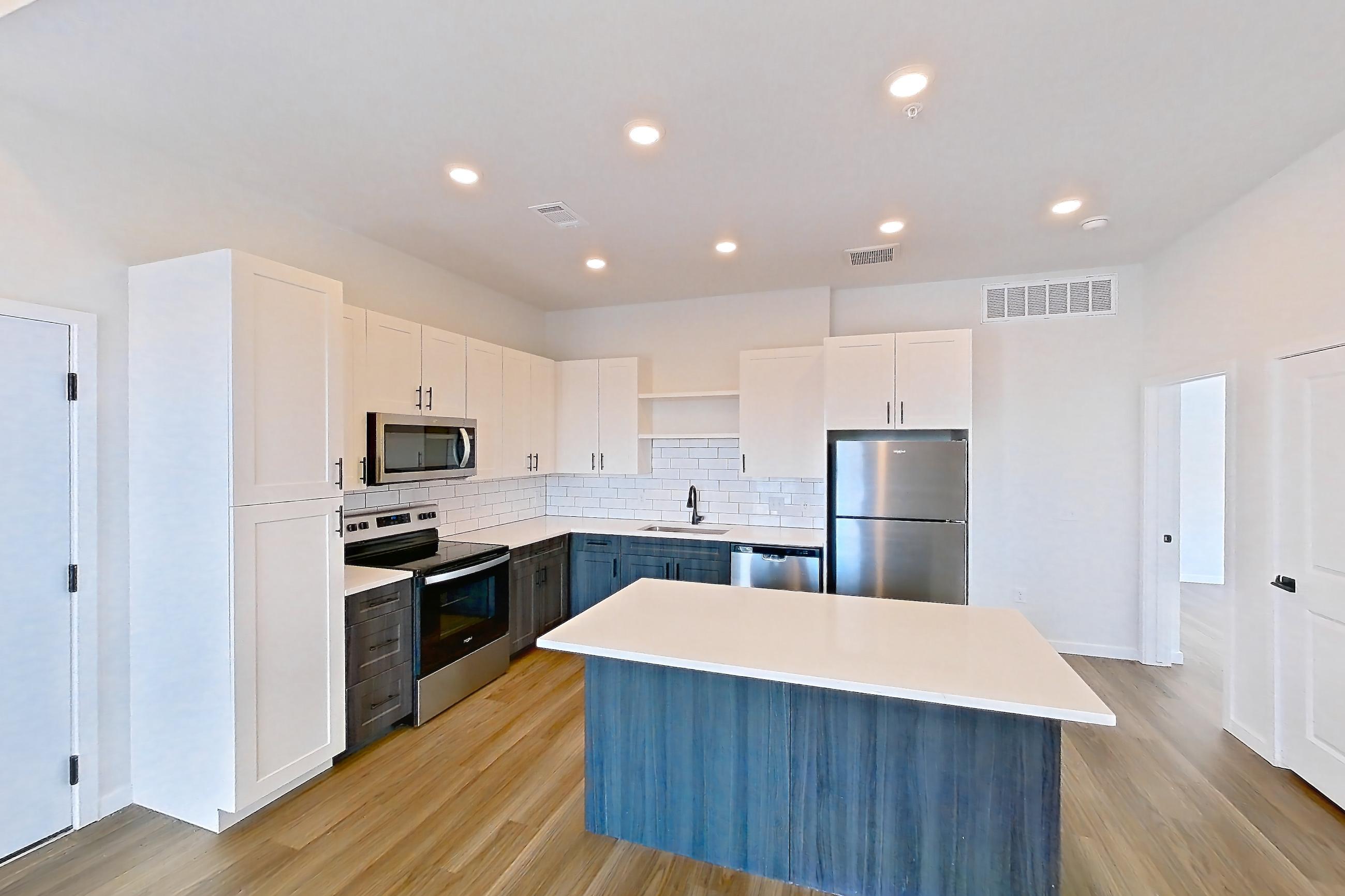 Living space with dishwasher, electric range, light countertops, light wood-finish flooring, oven/range, refrigerator, and stainless steel appliances, Apartment 06-302 at Marlon at Central Park