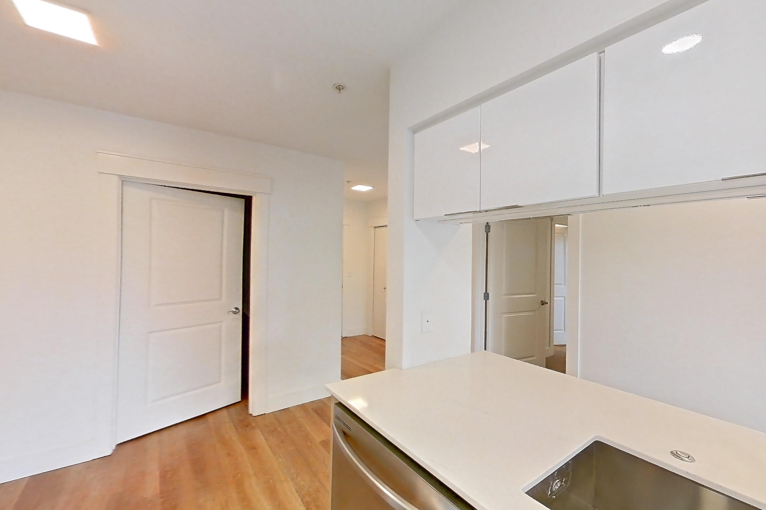 Kitchen with dishwasher, electric range, light countertops, light stone countertops, light wood-finish flooring, oven/range, refrigerator, and stainless steel appliances, Apartment 0004 at Eastlake 2851