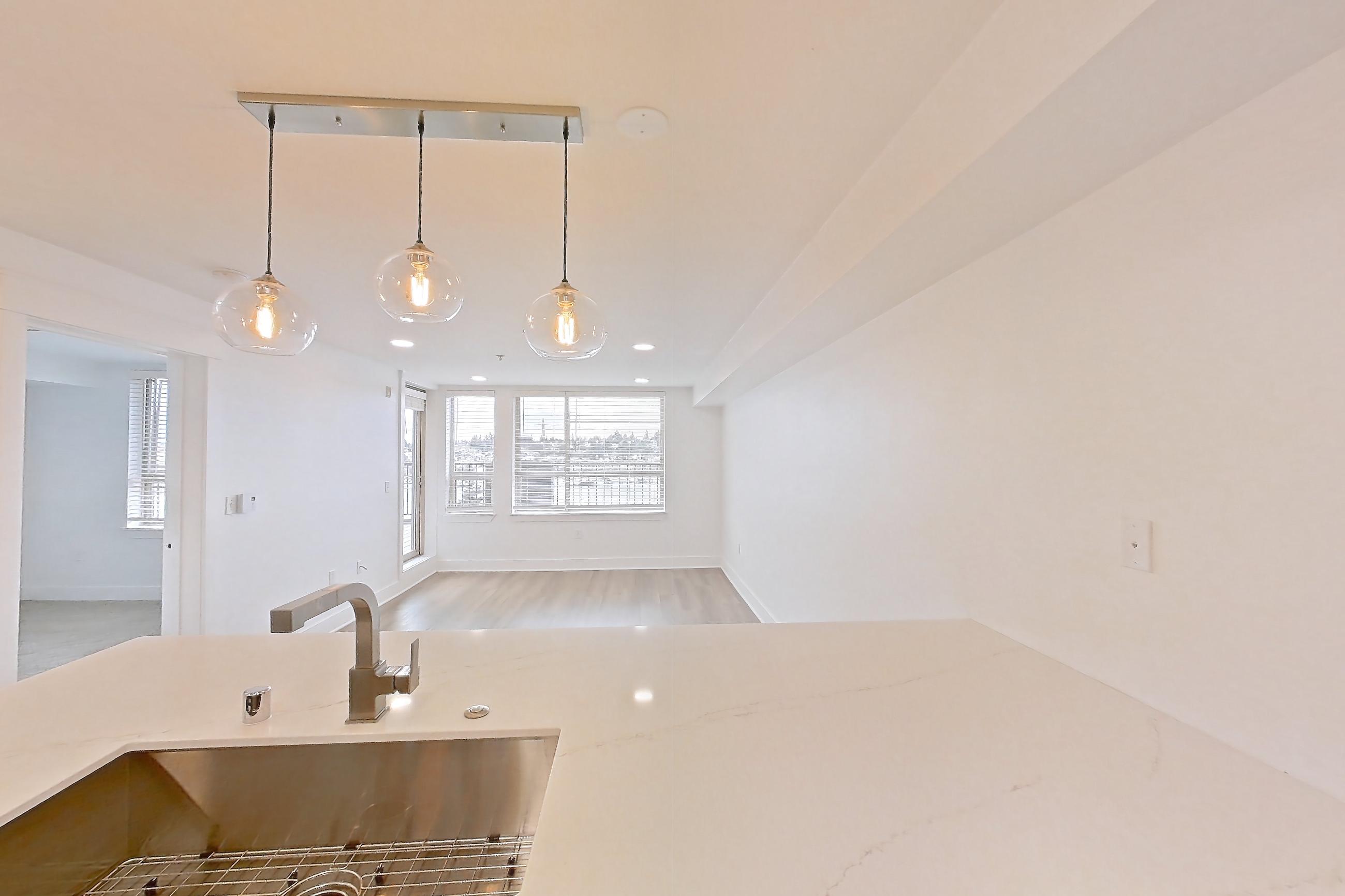 Kitchen with dishwasher, electric range, light countertops, light stone countertops, light wood-finish flooring, microwave, oven/range, refrigerator, and stainless steel appliances, Apartment 0328 at Eastlake 2851
