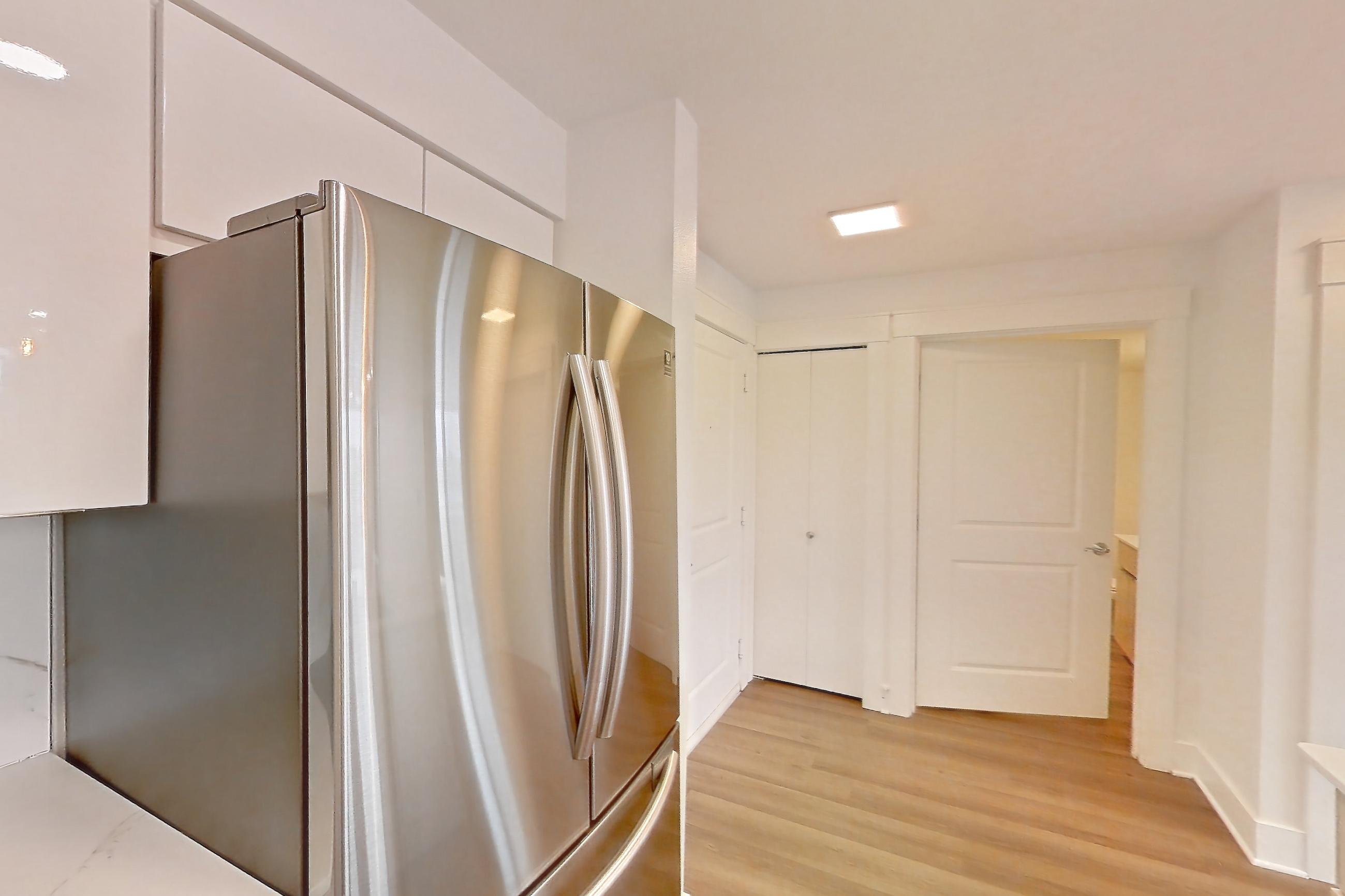 Kitchen with dishwasher, electric range, light countertops, light stone countertops, light wood-finish flooring, microwave, oven/range, refrigerator, and stainless steel appliances, Apartment 0328 at Eastlake 2851