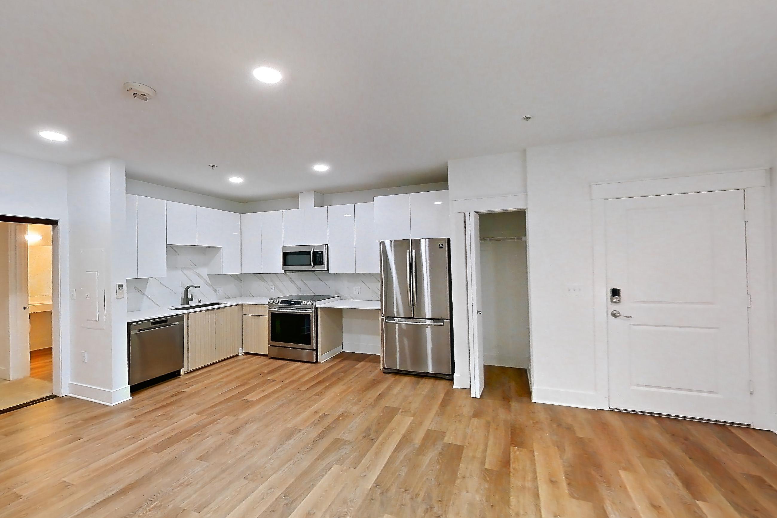 Living room with light countertops, light wood-finish flooring, oven/range, refrigerator, and stainless steel appliances, Apartment 2835B at Eastlake 2851