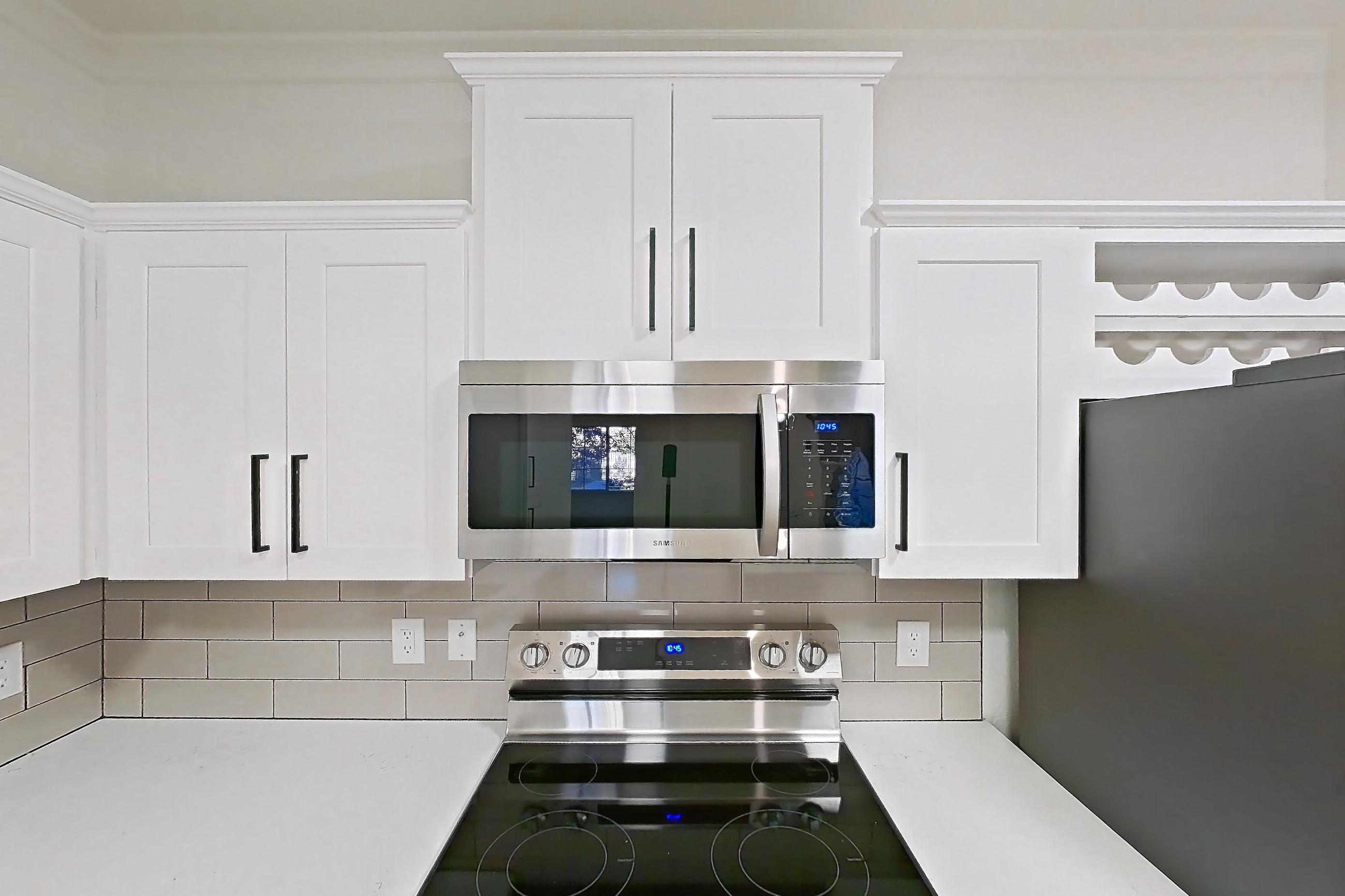 Kitchen with dishwasher, electric range, light countertops, light stone countertops, light wood-finish flooring, microwave, oven/range, refrigerator, and stainless steel appliances, Apartment 30-110 at Terracina