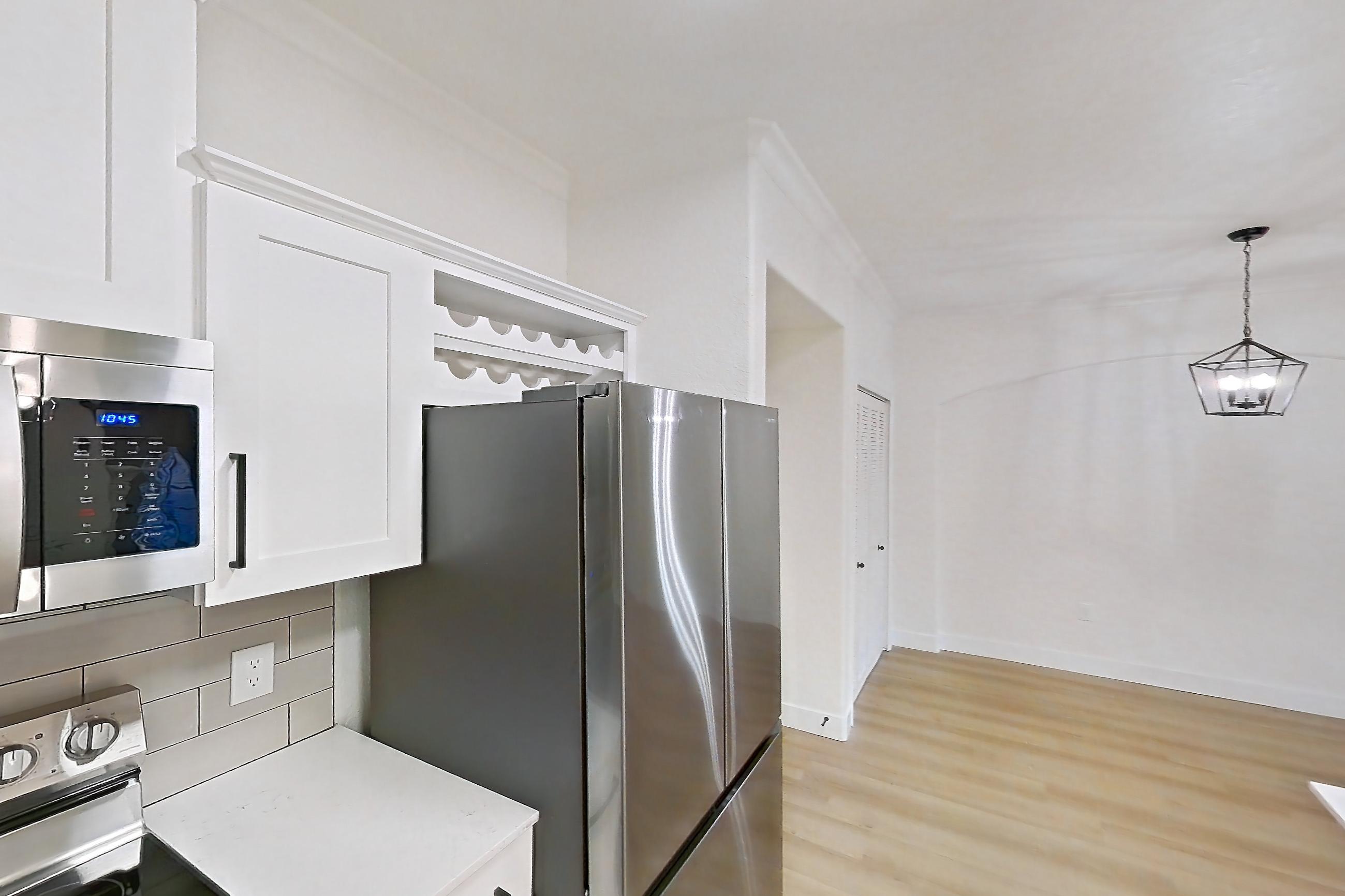 Kitchen with dishwasher, electric range, light countertops, light stone countertops, light wood-finish flooring, microwave, oven/range, refrigerator, and stainless steel appliances, Apartment 30-110 at Terracina