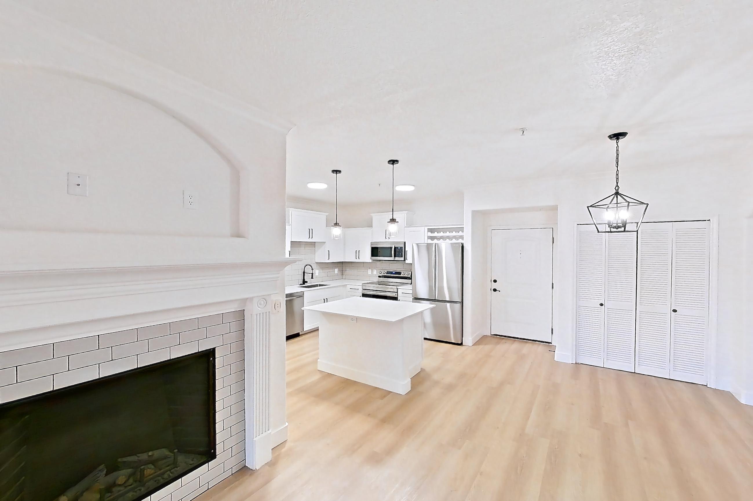 Living space with dishwasher, electric range, fireplace, light countertops, light wood-finish flooring, oven/range, refrigerator, stainless steel appliances, and tile fireplace, Apartment 30-110 at Terracina