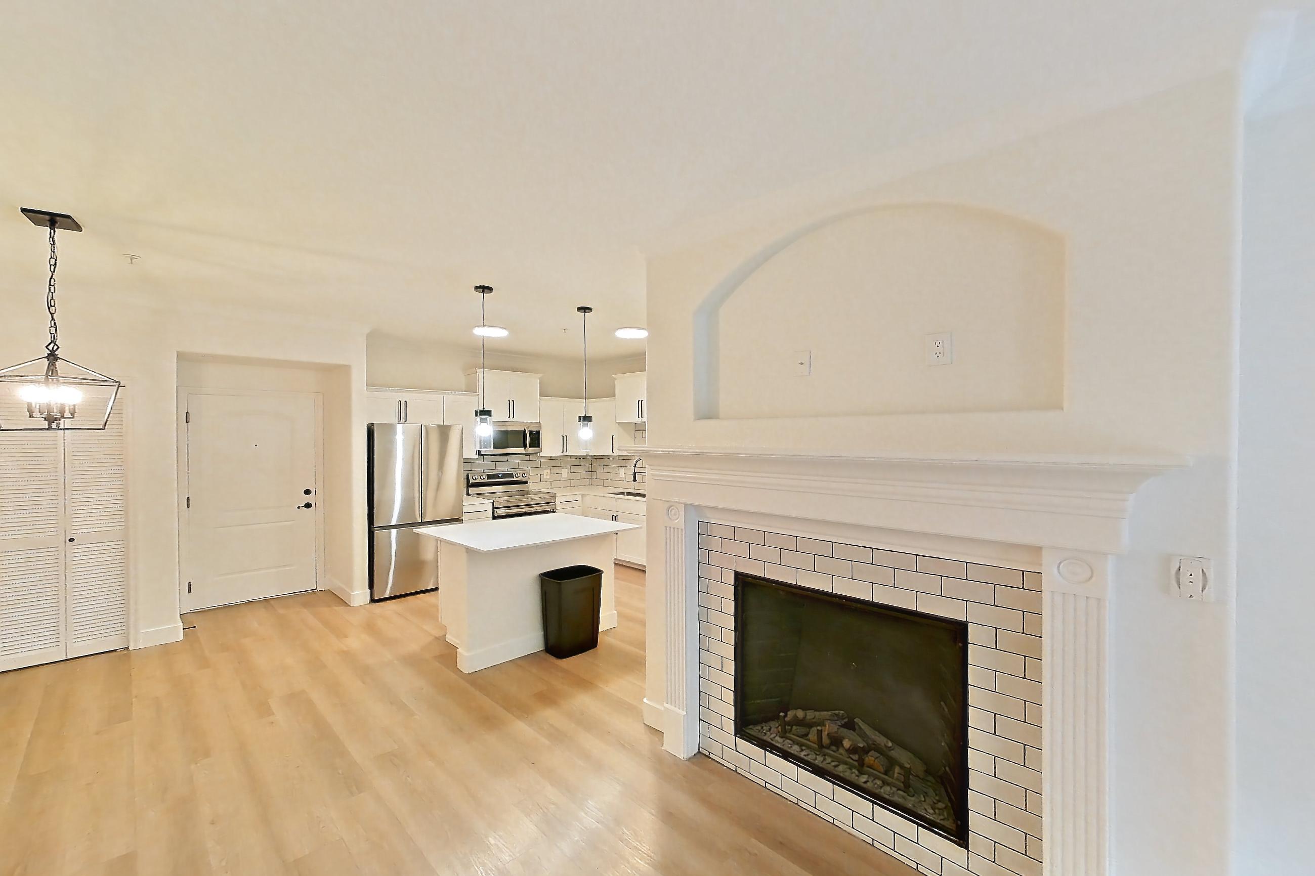 Living space with electric range, fireplace, light wood-finish flooring, oven/range, refrigerator, stainless steel appliances, and tile fireplace, Apartment 30-119 at Terracina