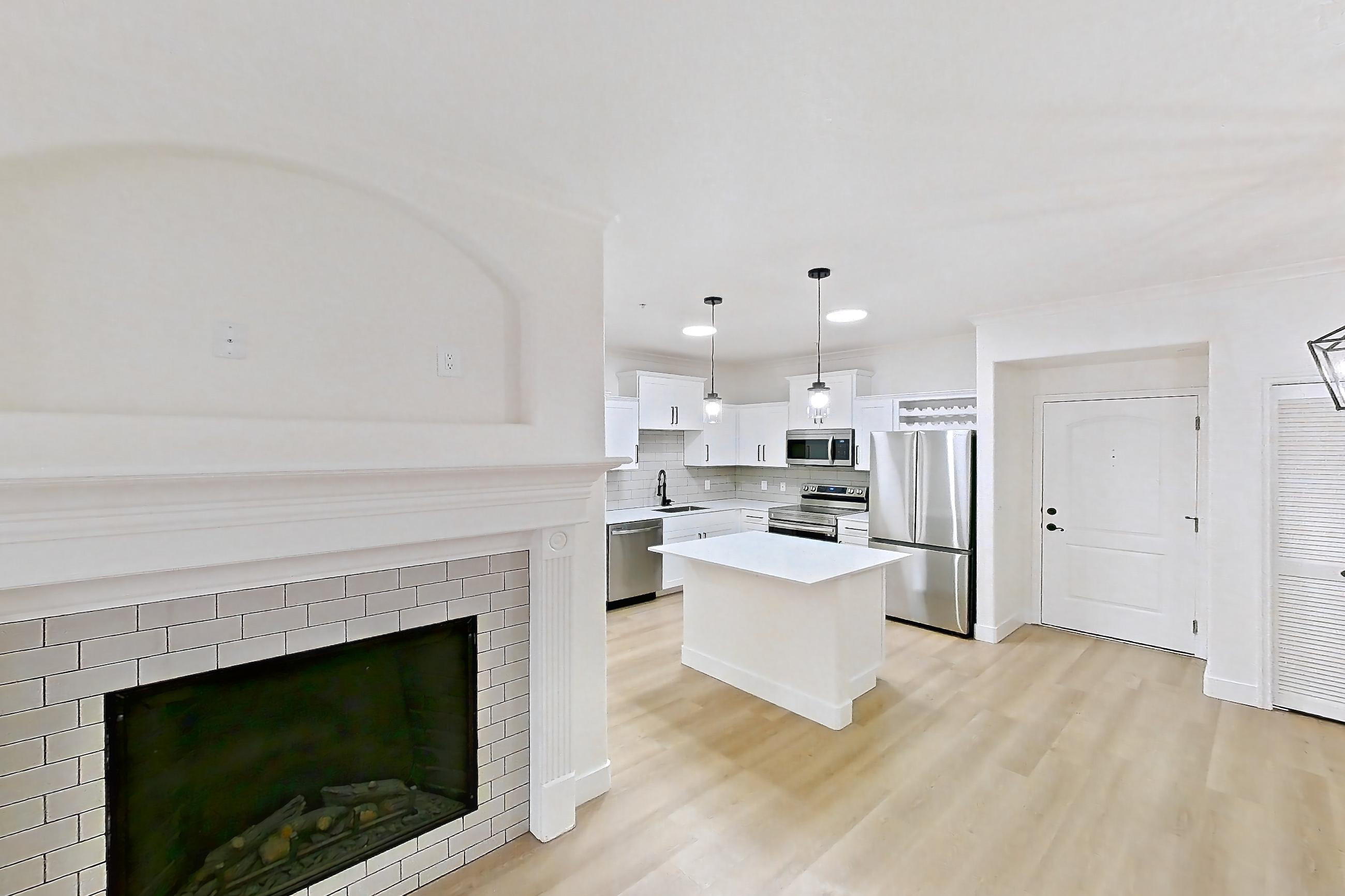 Living space with dishwasher, electric range, fireplace, light wood-finish flooring, oven/range, refrigerator, stainless steel appliances, and tile fireplace, Apartment 30-121 at Terracina