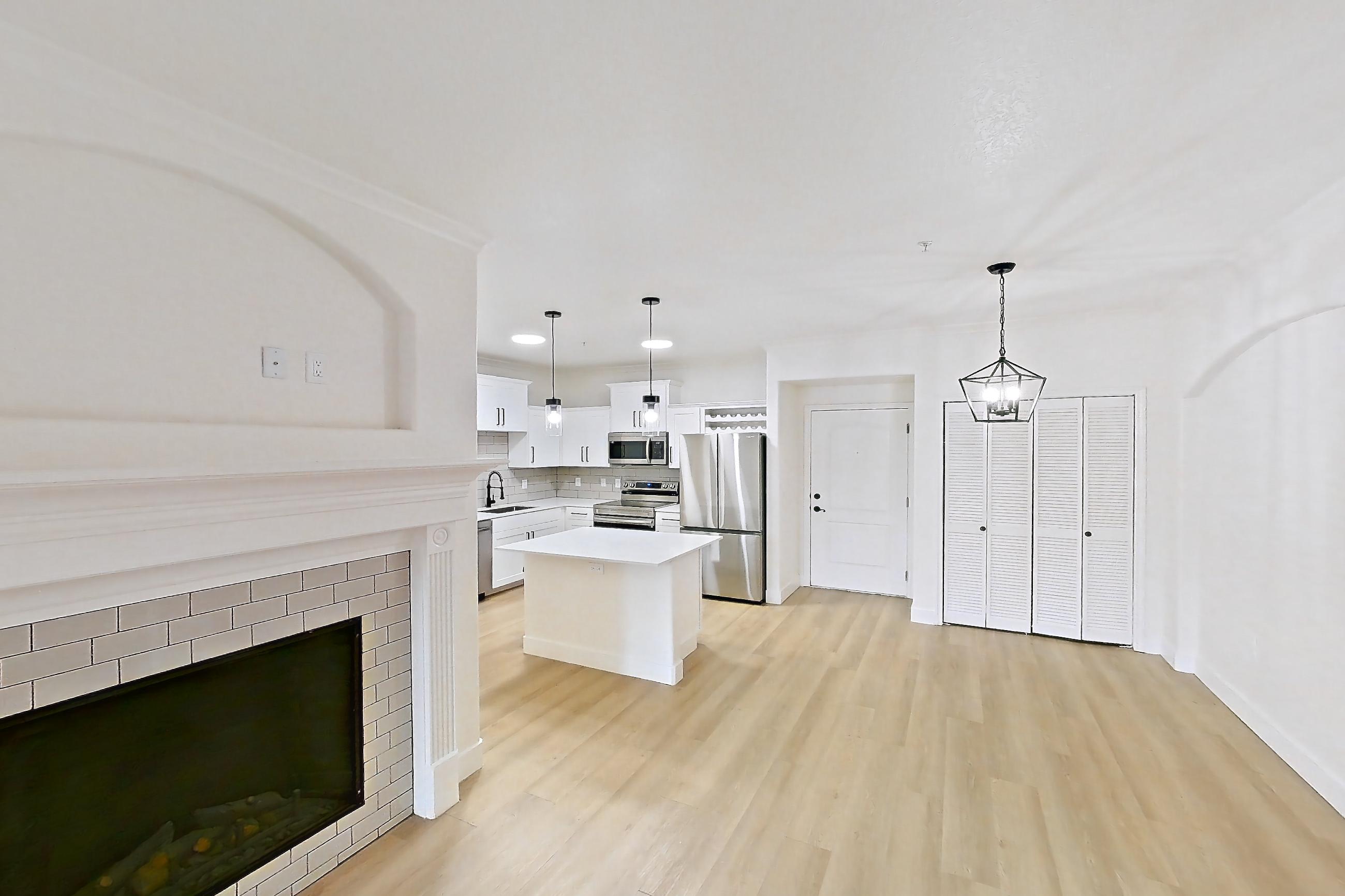 Living space with dishwasher, electric range, fireplace, light wood-finish flooring, oven/range, refrigerator, stainless steel appliances, and tile fireplace, Apartment 30-210 at Terracina