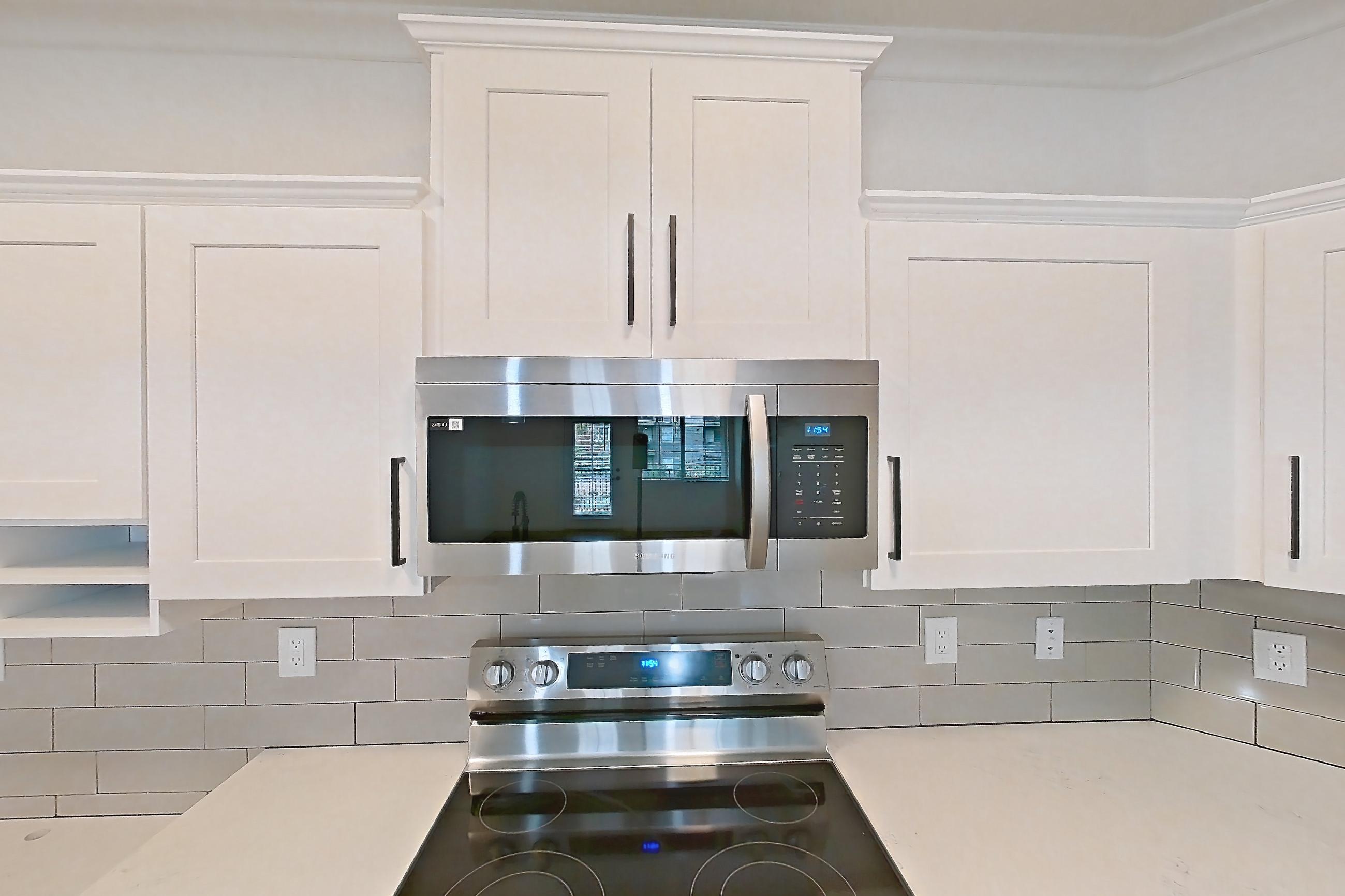 Kitchen with dishwasher, electric range, light countertops, light stone countertops, light wood-finish flooring, microwave, oven/range, refrigerator, and stainless steel appliances, Apartment 50-206 at Terracina