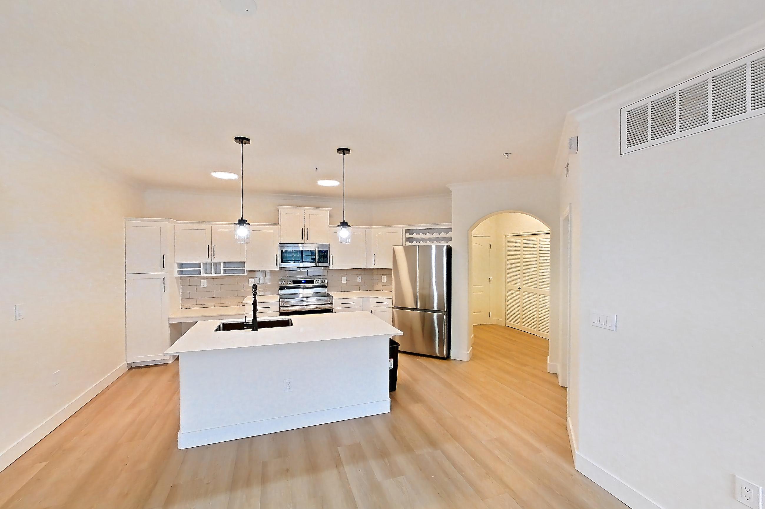 Living space with electric range, kitchen island, light stone countertops, light wood-finish flooring, oven/range, refrigerator, and stainless steel appliances, Apartment 50-206 at Terracina
