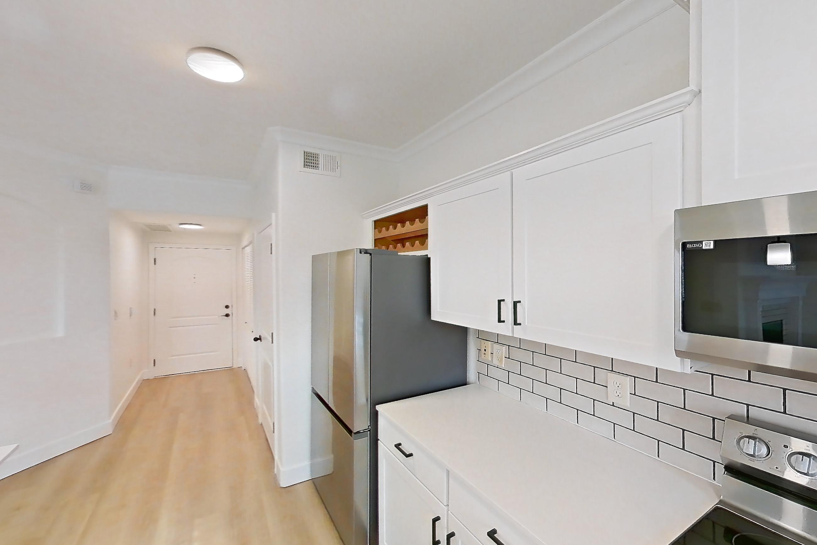Kitchen with dishwasher, electric range, light countertops, light stone countertops, light wood-finish flooring, microwave, oven/range, refrigerator, and stainless steel appliances, Apartment 60-207 at Terracina