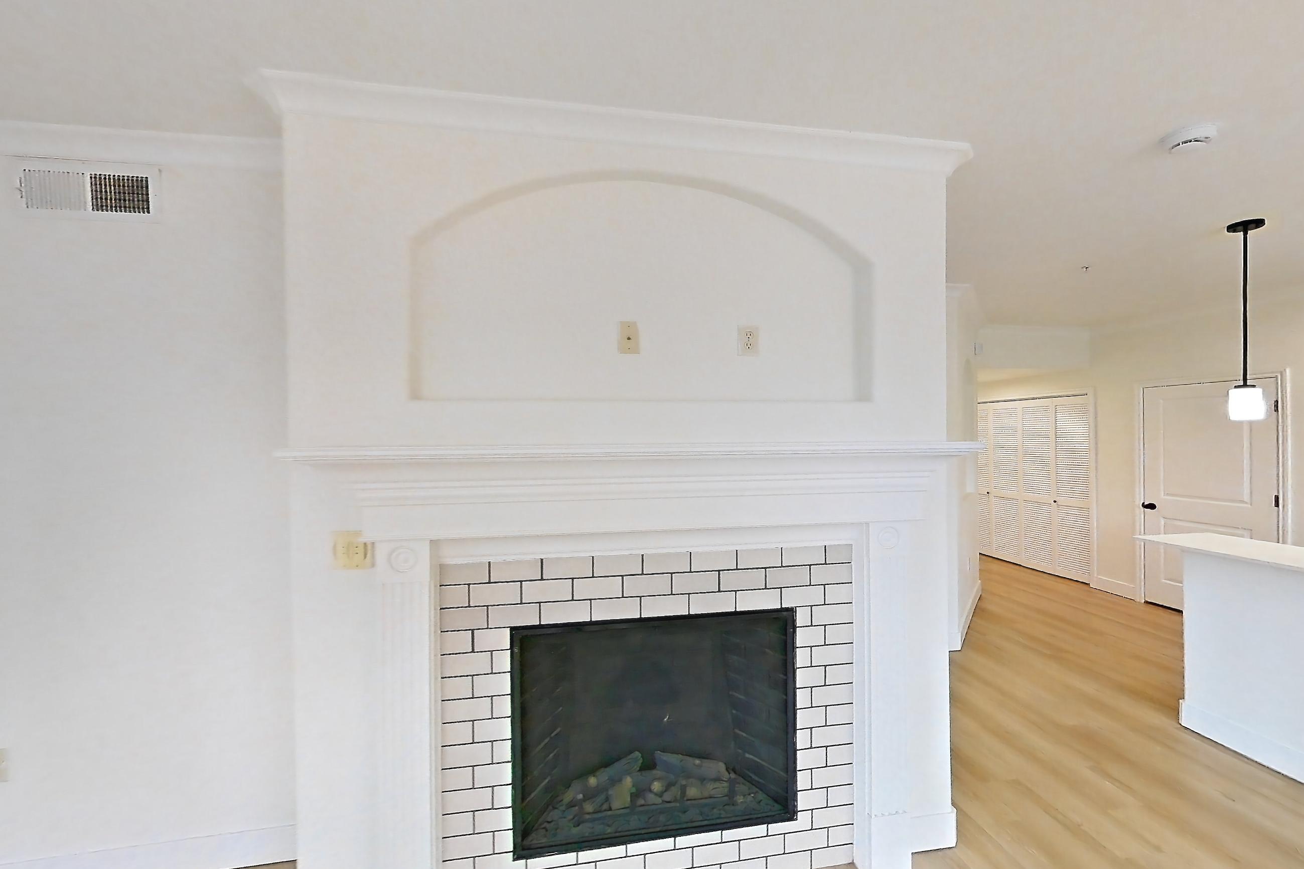 Living space with electric range, fireplace, light countertops, light wood-finish flooring, oven/range, refrigerator, stainless steel appliances, and tile fireplace, Apartment 60-207 at Terracina