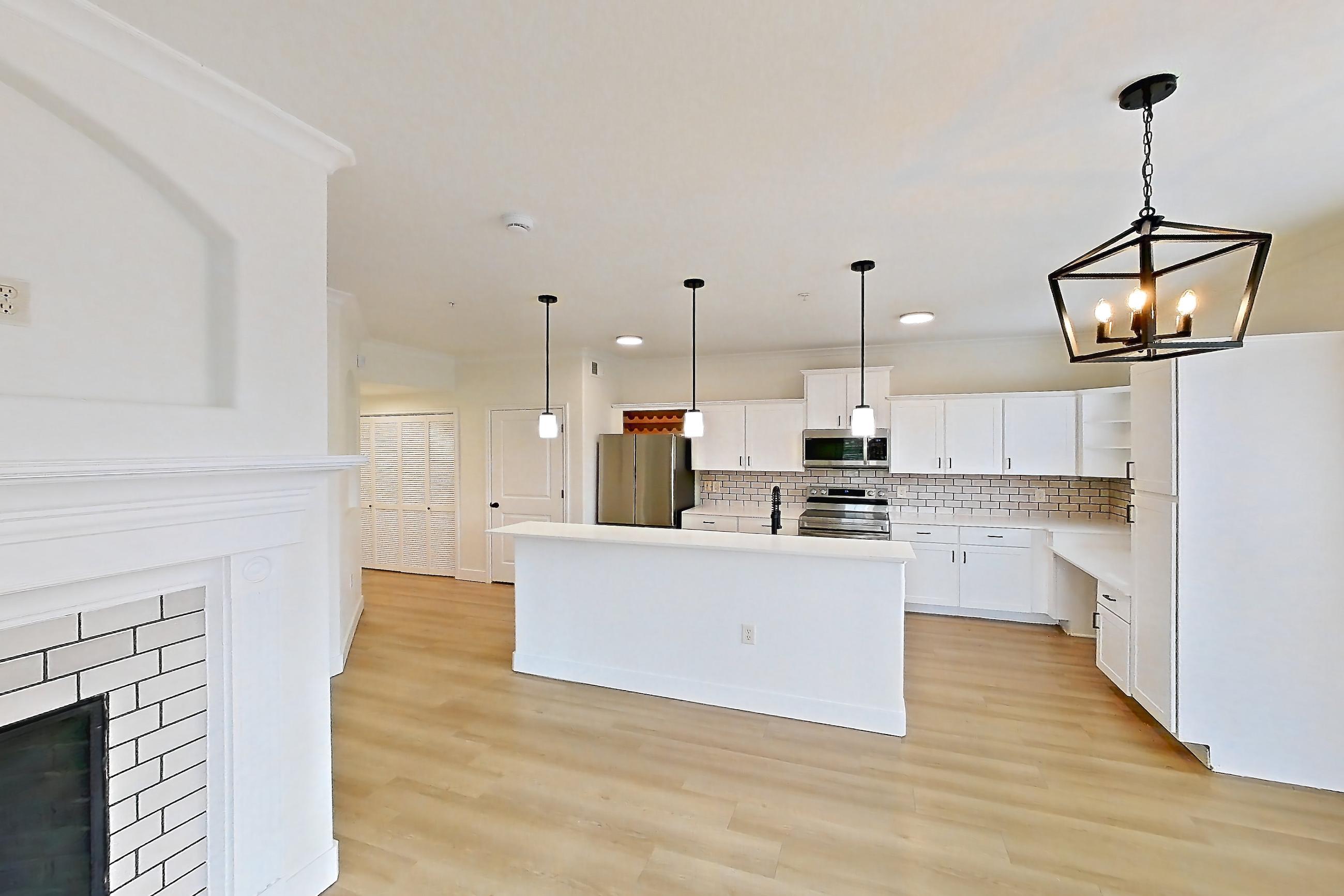 Living space with electric range, fireplace, light countertops, light wood-finish flooring, oven/range, refrigerator, stainless steel appliances, and tile fireplace, Apartment 60-207 at Terracina