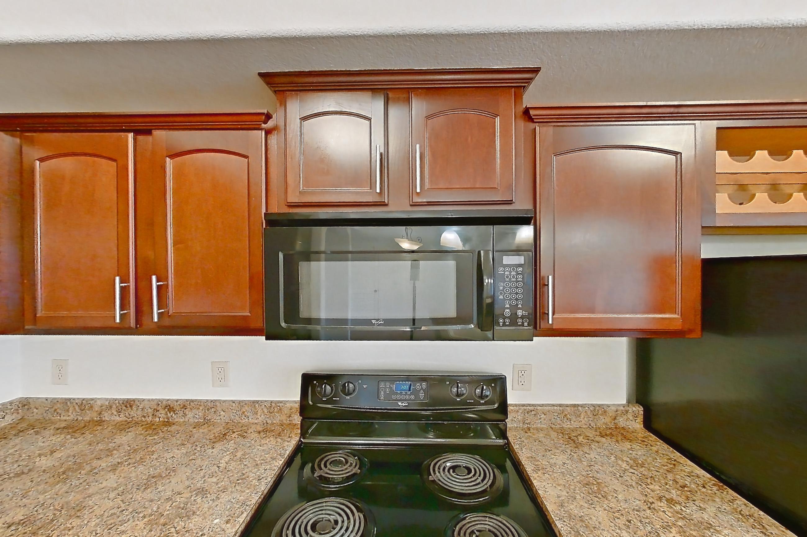 Kitchen with black appliances, dishwasher, electric range, light countertops, light stone countertops, light tile flooring, microwave, oven/range, and refrigerator, Apartment 60-209 at Terracina