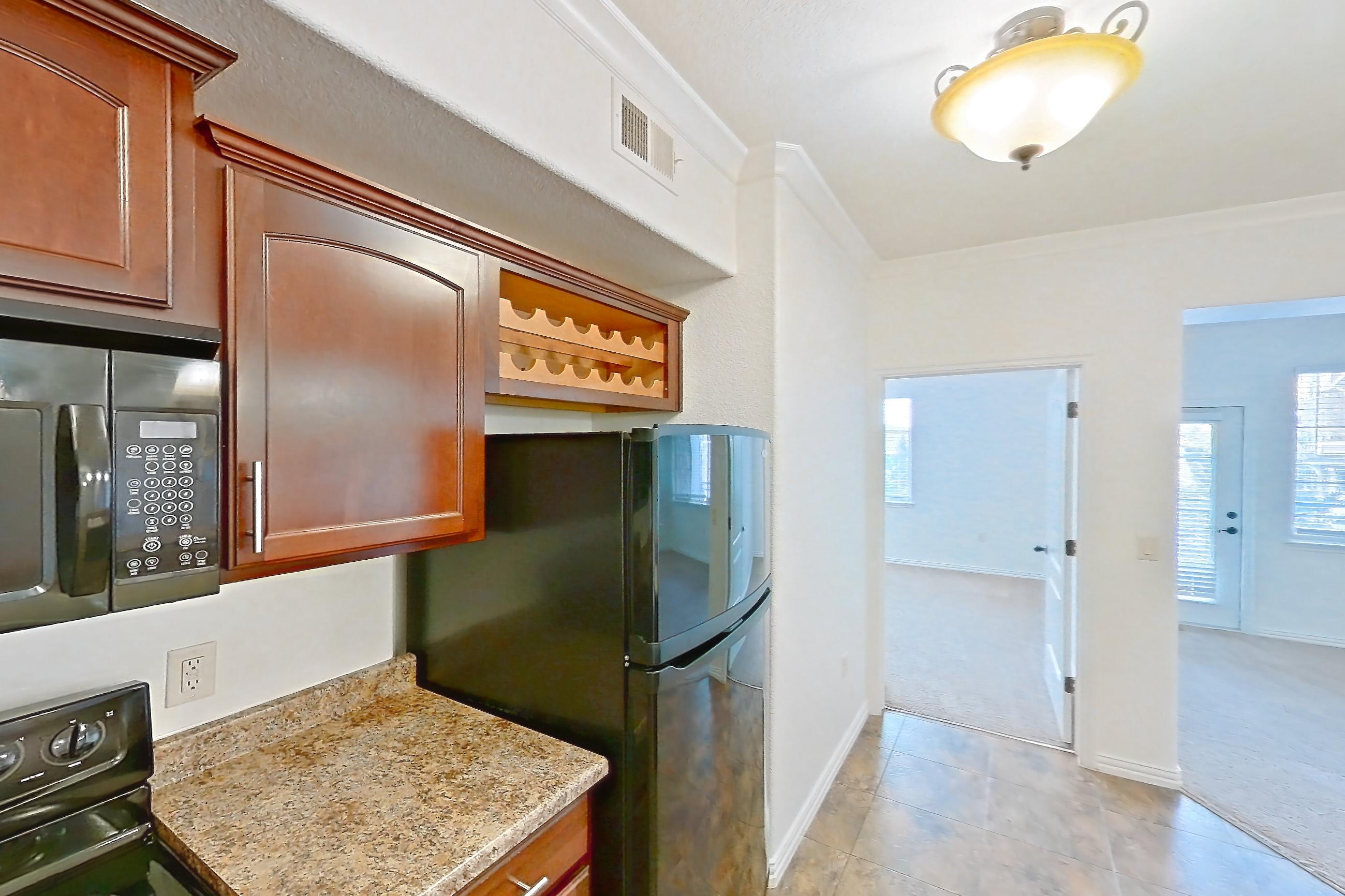 Kitchen with black appliances, dishwasher, electric range, light countertops, light stone countertops, light tile flooring, microwave, oven/range, and refrigerator, Apartment 60-209 at Terracina