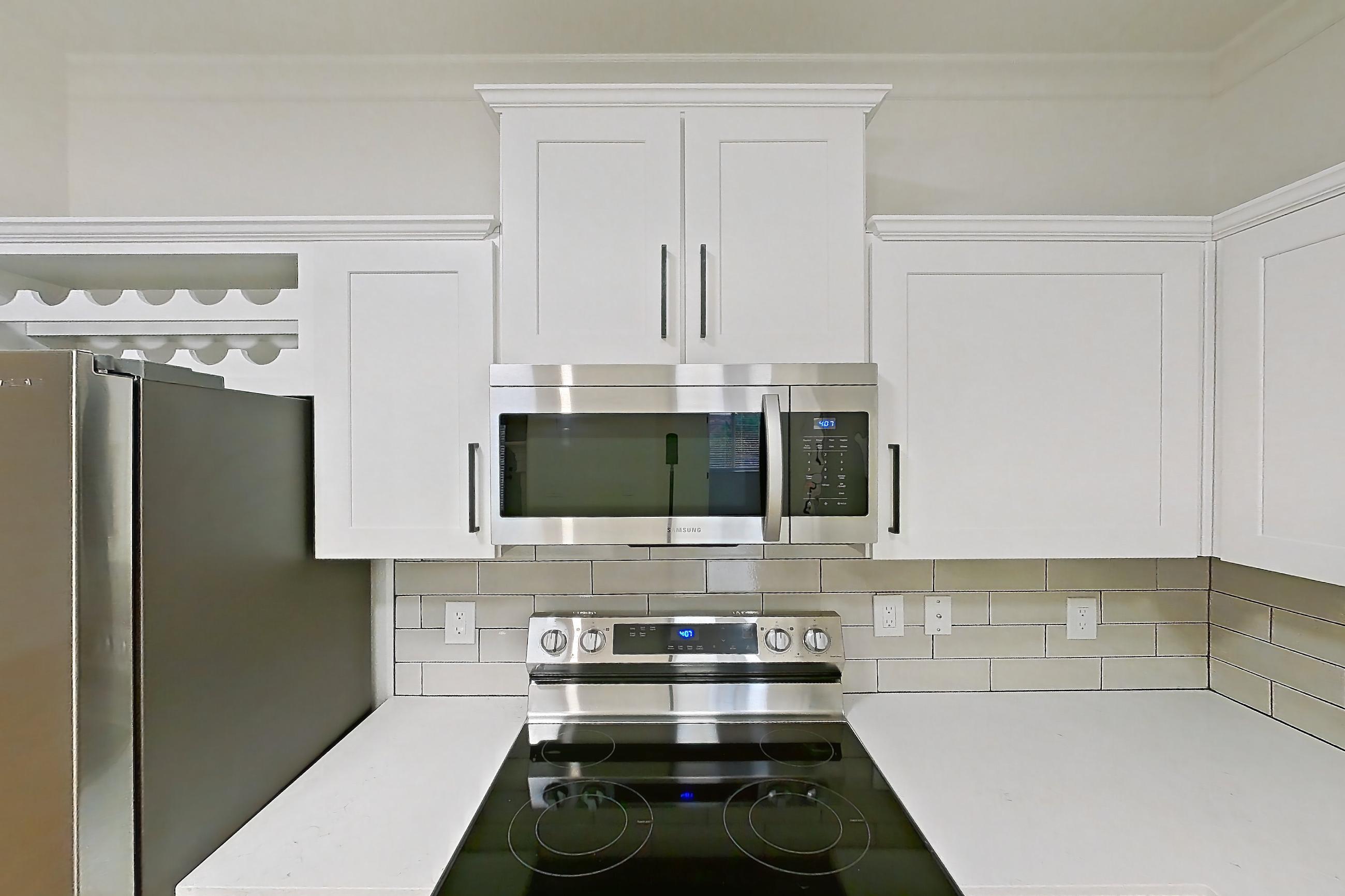 Kitchen with dishwasher, electric range, light countertops, light stone countertops, light wood-finish flooring, microwave, oven/range, refrigerator, and stainless steel appliances, Apartment 70-119 at Terracina