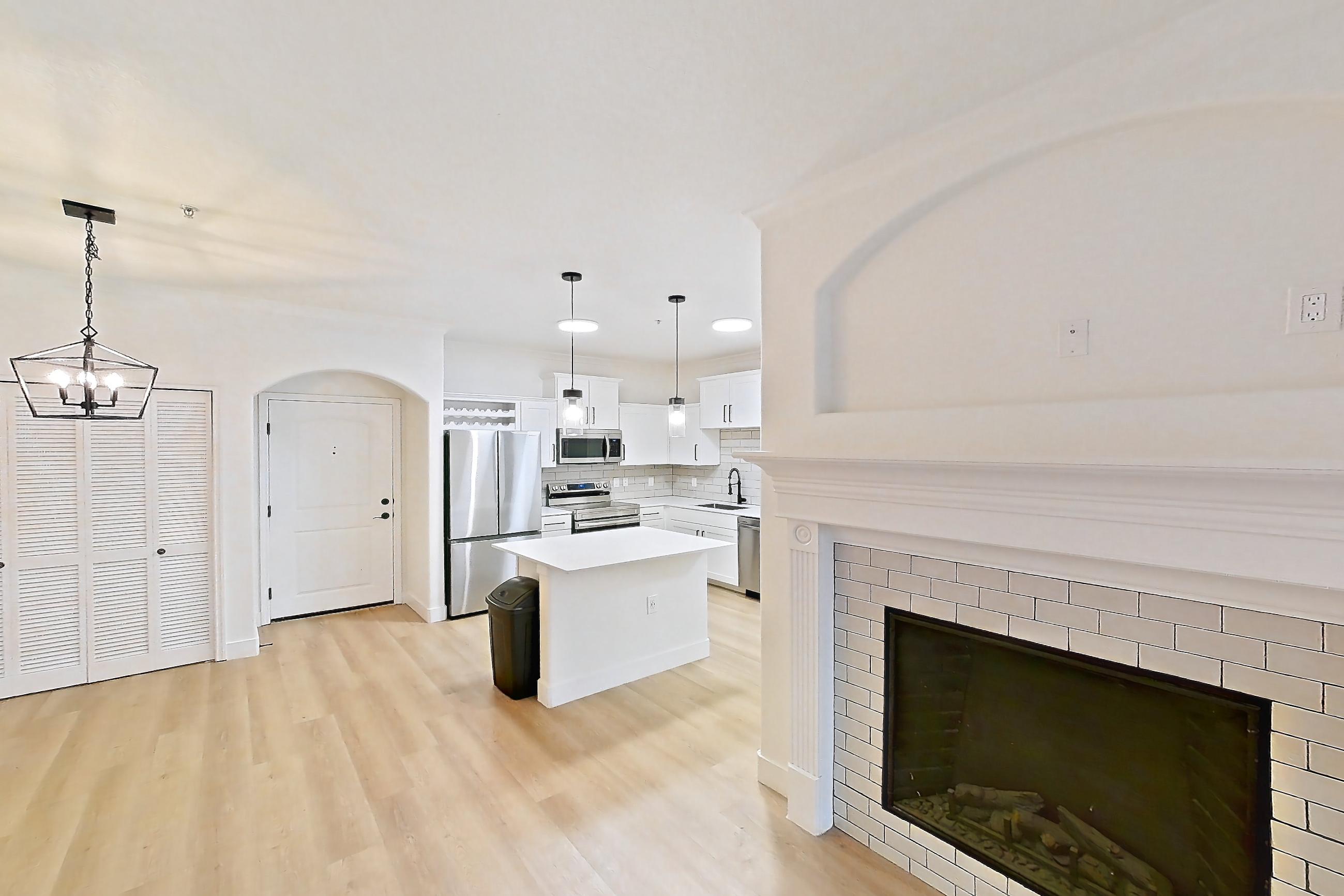 Living space with dishwasher, electric range, fireplace, light countertops, light wood-finish flooring, oven/range, refrigerator, stainless steel appliances, and tile fireplace, Apartment 70-119 at Terracina
