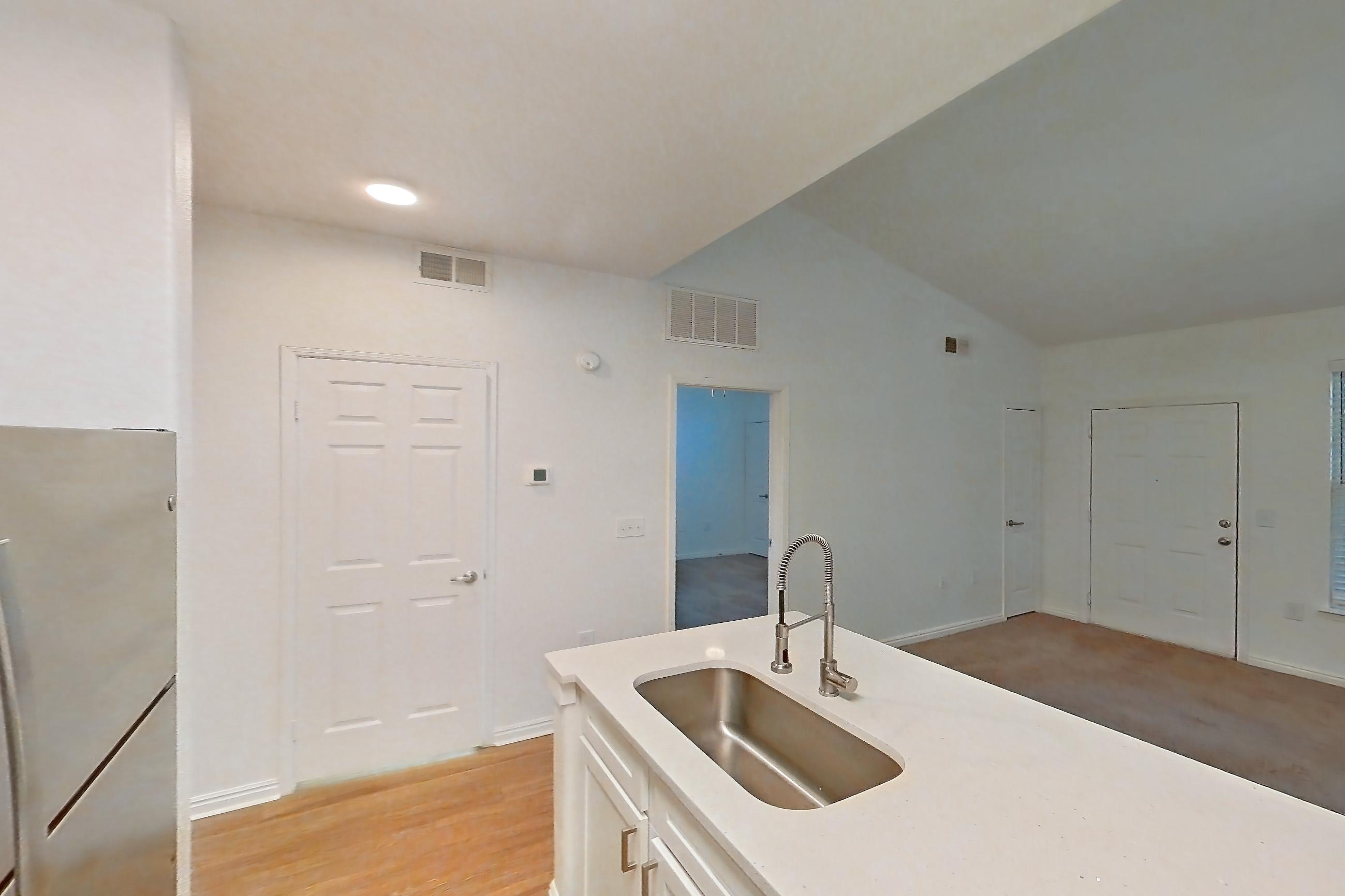 Kitchen with dishwasher, electric range, in-unit laundry, light stone countertops, light wood-finish flooring, microwave, oven/range, refrigerator, and stainless steel appliances, Apartment 03-203 at Eagle Ridge