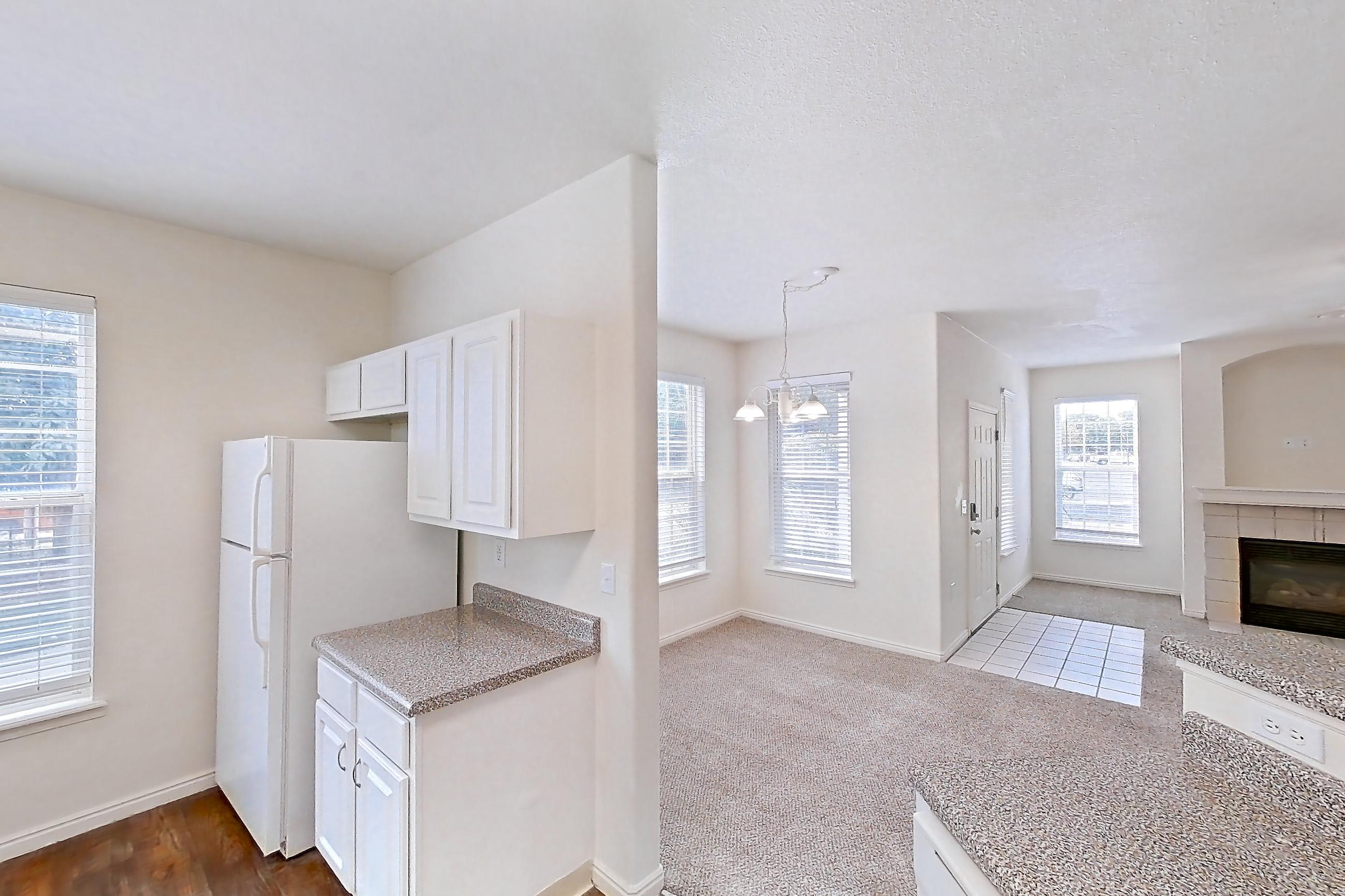 Kitchen with dark countertops, dark wood-finish flooring, dishwasher, electric range, fireplace, oven/range, range hood, tile fireplace, and white appliances, Apartment 01-105 at Eagle Ridge
