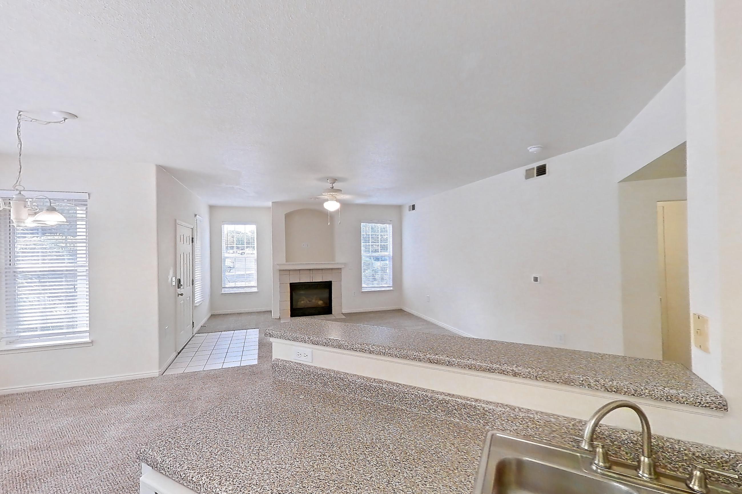 Kitchen with dark countertops, dark wood-finish flooring, dishwasher, electric range, fireplace, oven/range, range hood, tile fireplace, and white appliances, Apartment 01-105 at Eagle Ridge