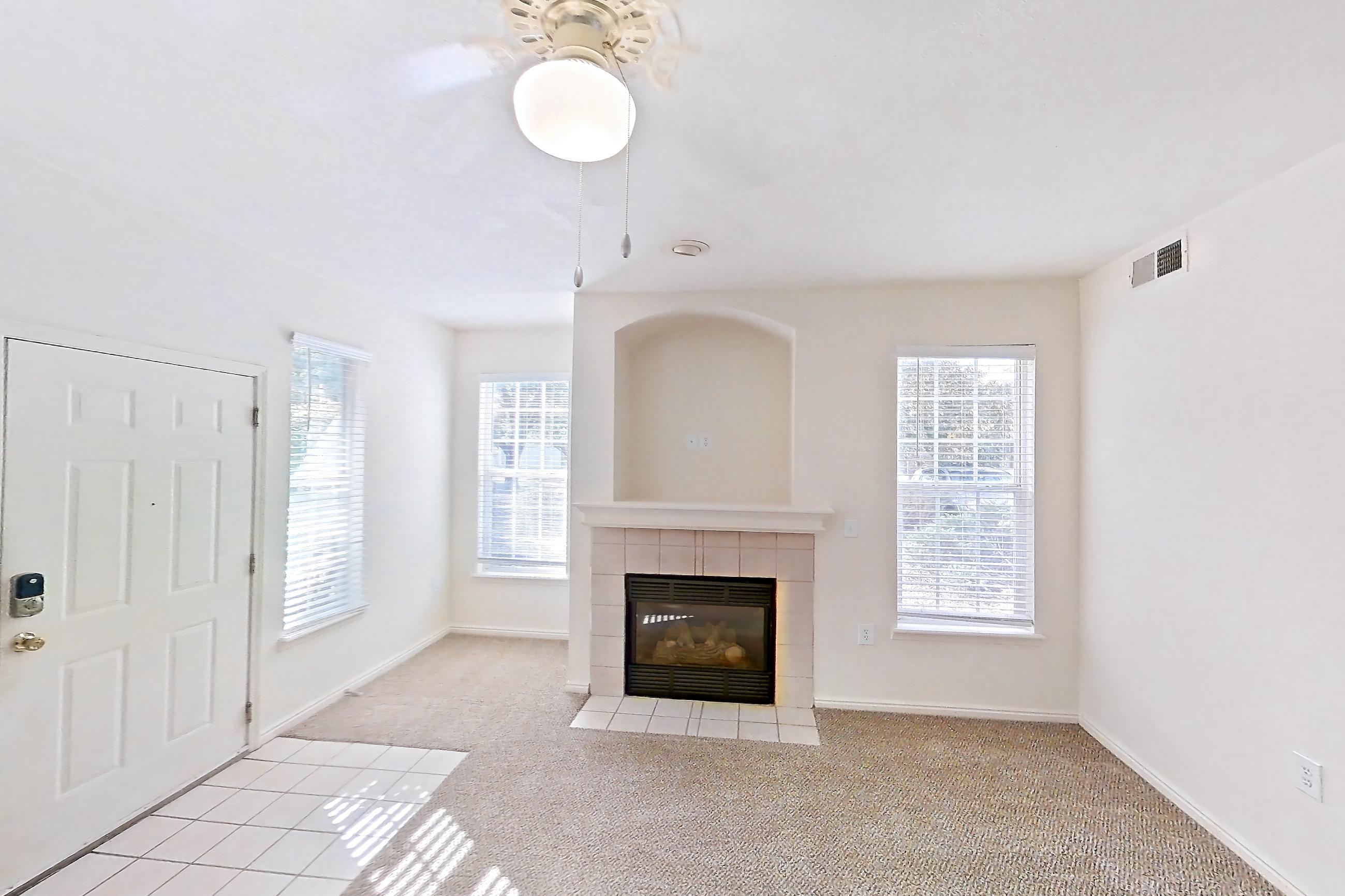 Living space with fireplace, light carpet, light tile flooring, oven/range, tile fireplace, and white appliances, Apartment 01-105 at Eagle Ridge