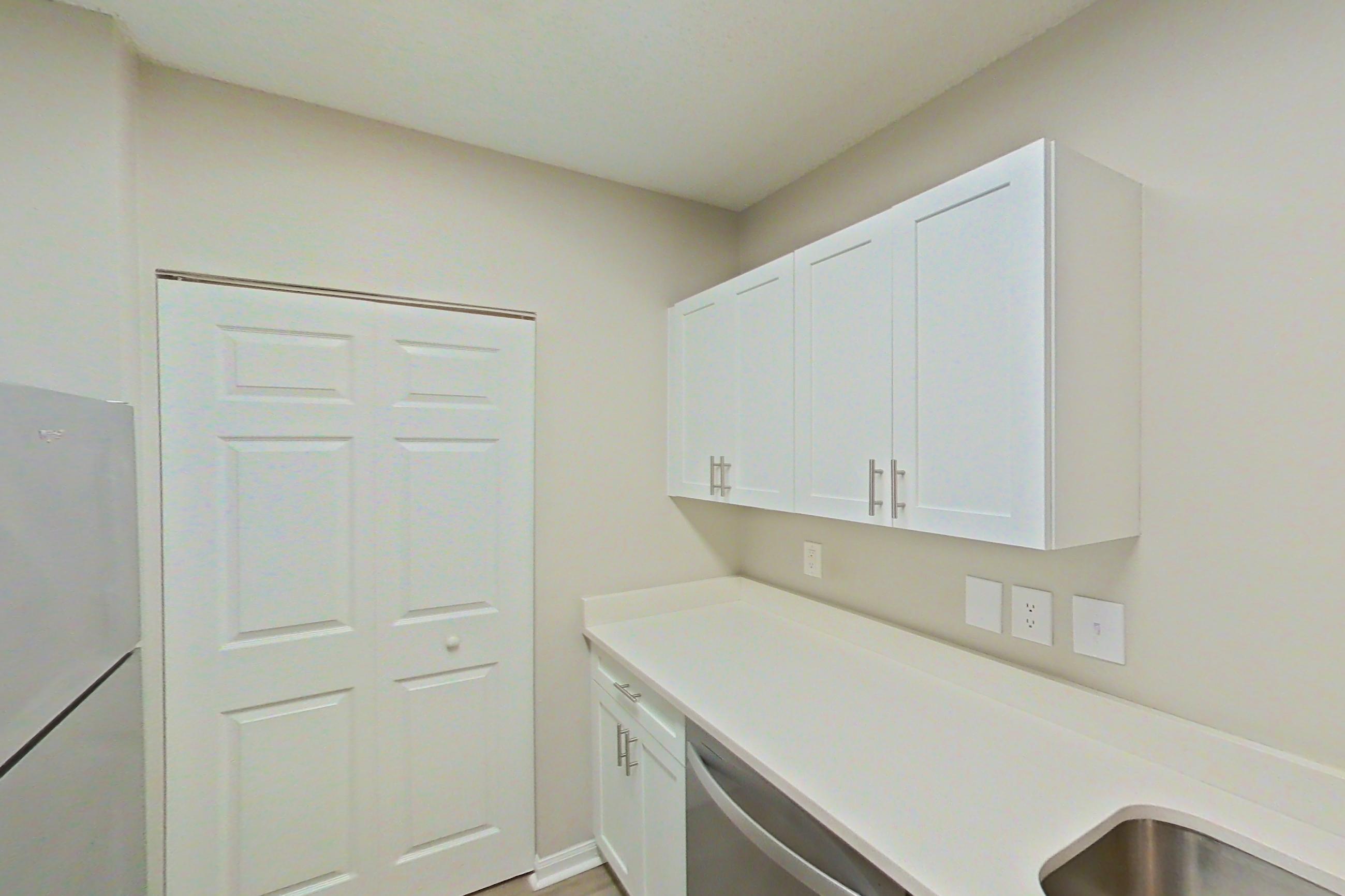 Kitchen with dishwasher, electric range, light countertops, light stone countertops, light wood-finish flooring, refrigerator, and stainless steel appliances, Apartment 15-207 at Miramar Lakes