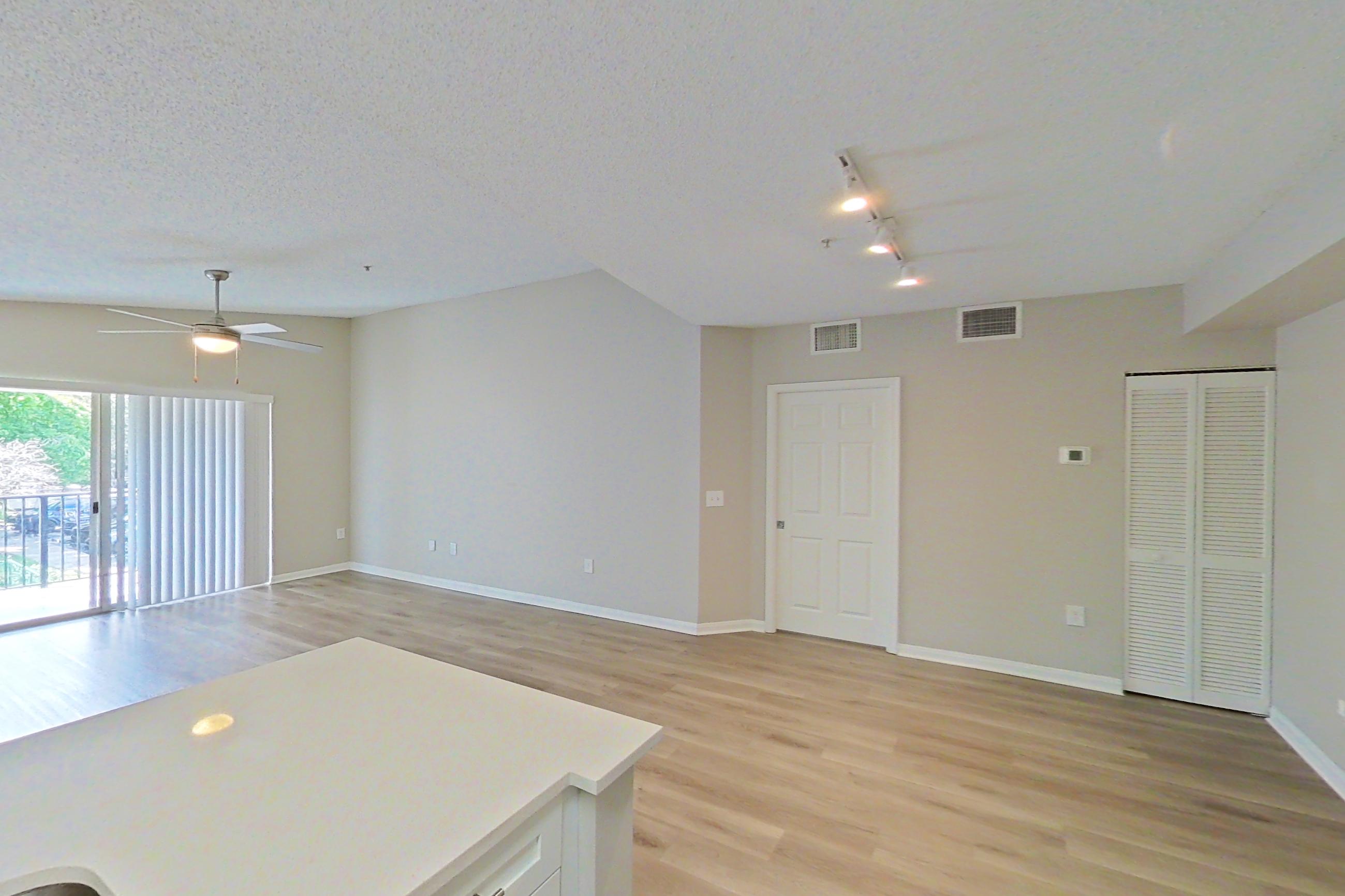 Kitchen with dishwasher, electric range, light countertops, light stone countertops, light wood-finish flooring, refrigerator, and stainless steel appliances, Apartment 15-207 at Miramar Lakes