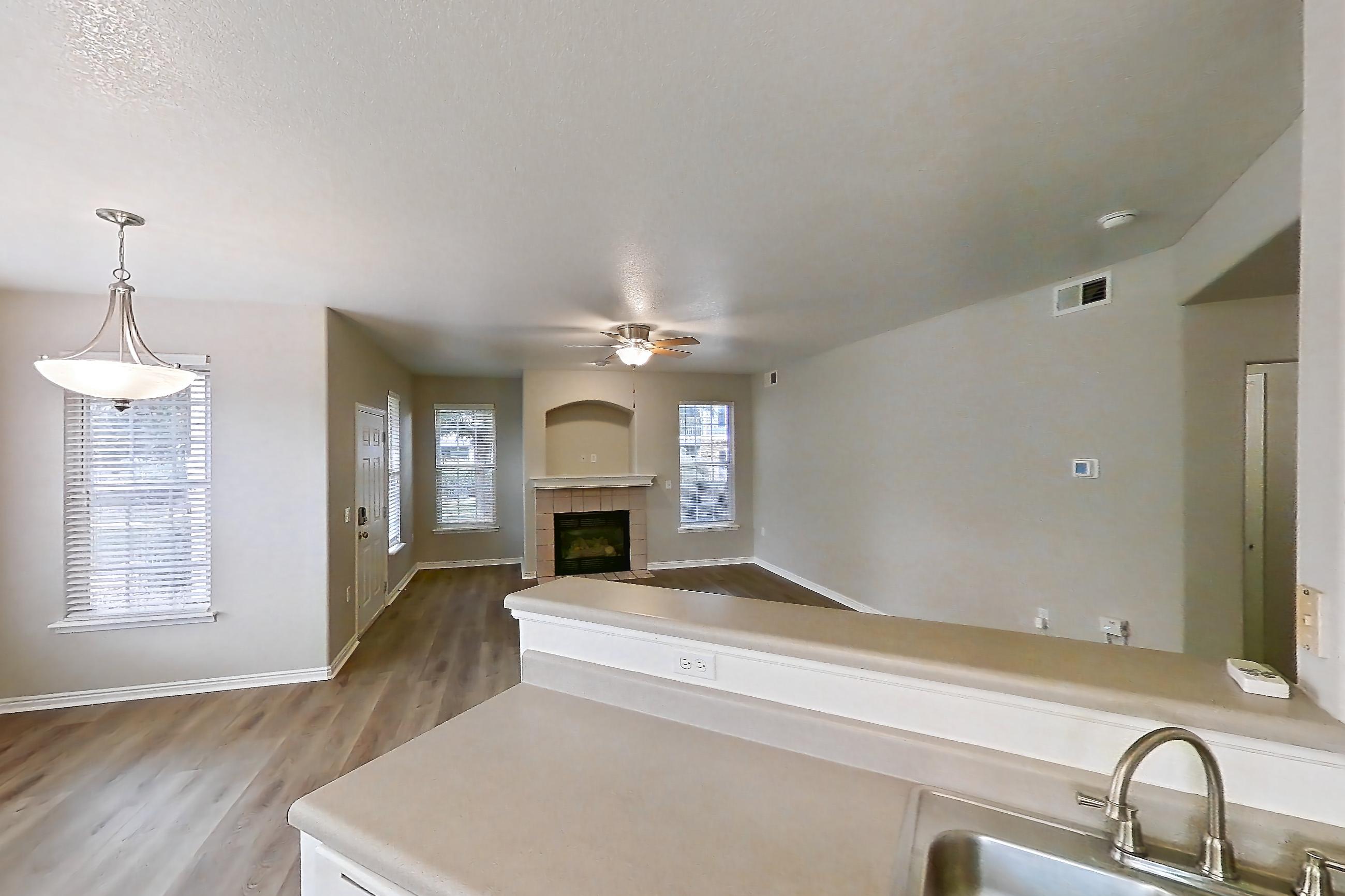 Kitchen with electric range, fireplace, light countertops, light wood-finish flooring, oven/range, range hood, tile fireplace, and white appliances, Apartment 12-105 at Eagle Ridge