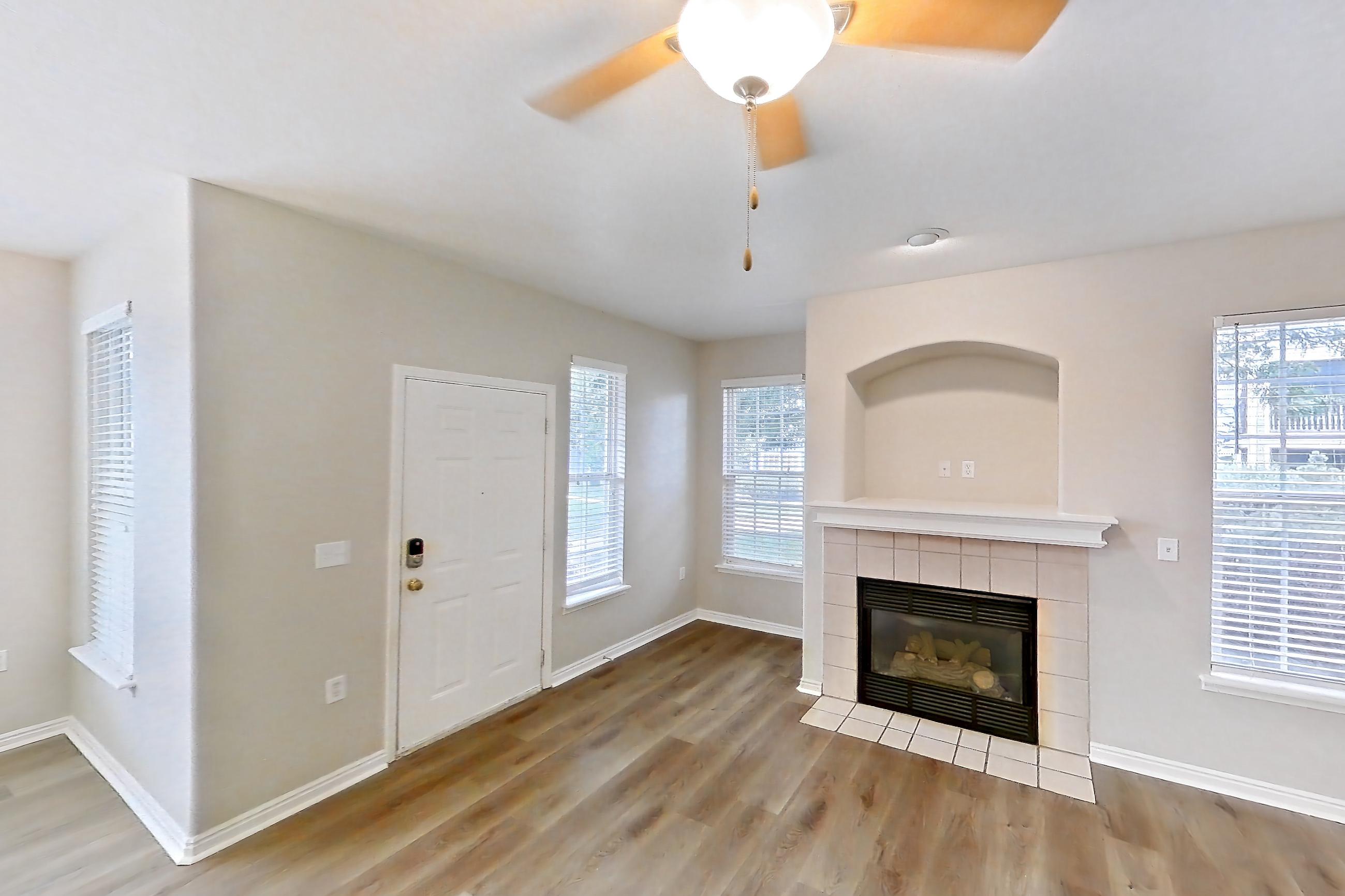 Living space with dark wood-finish flooring, electric range, fireplace, light wood-finish flooring, oven/range, tile fireplace, and white appliances, Apartment 12-105 at Eagle Ridge
