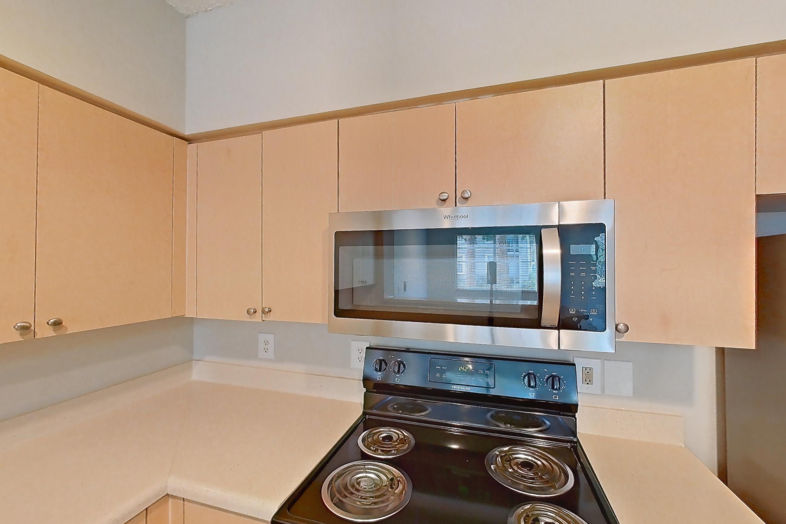 Kitchen with dishwasher, electric range, light countertops, light tile flooring, microwave, refrigerator, and stainless steel appliances, Apartment 06-108 at Miramar Lakes