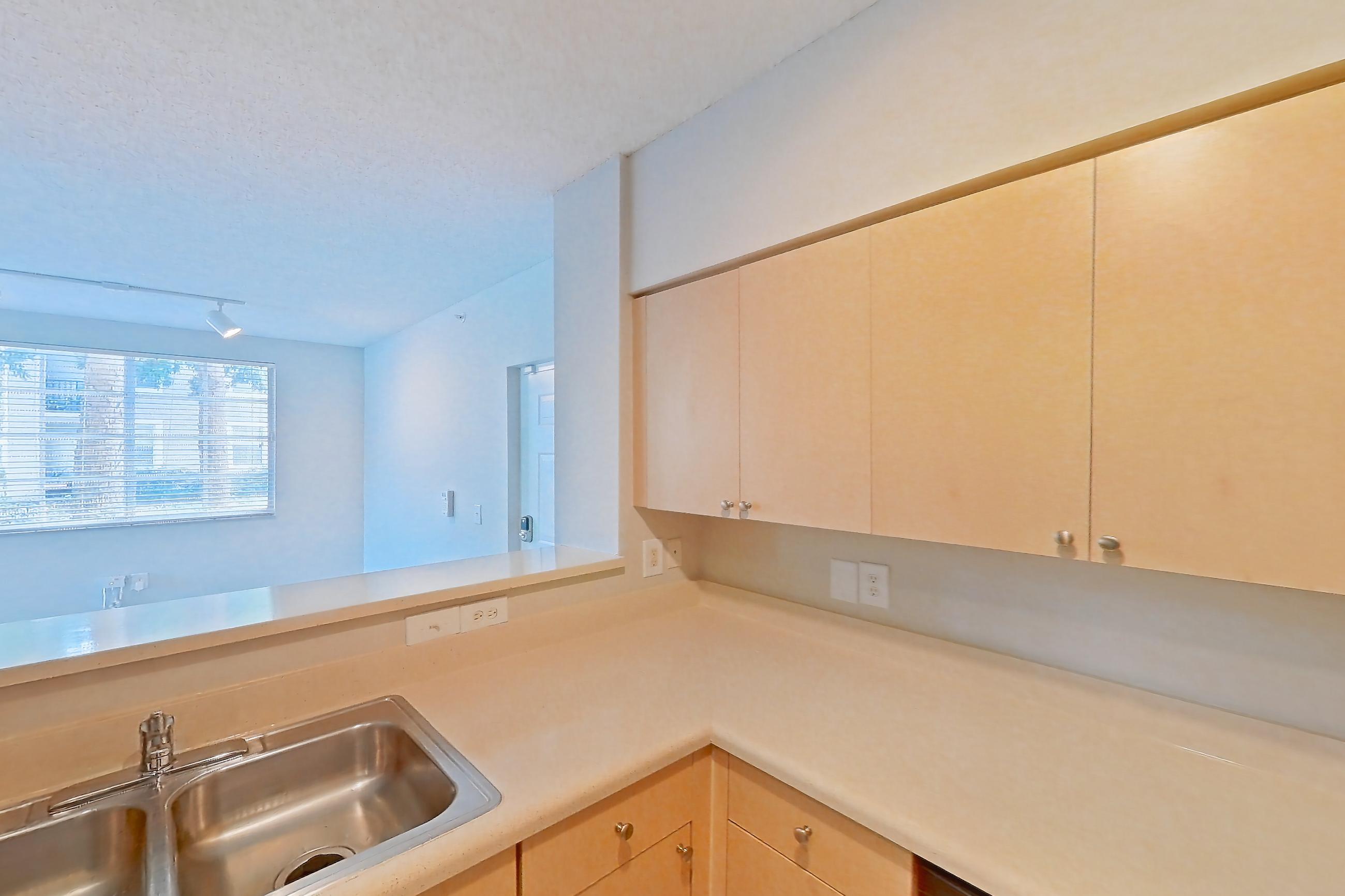 Kitchen with dishwasher, electric range, light countertops, light tile flooring, microwave, refrigerator, and stainless steel appliances, Apartment 06-108 at Miramar Lakes
