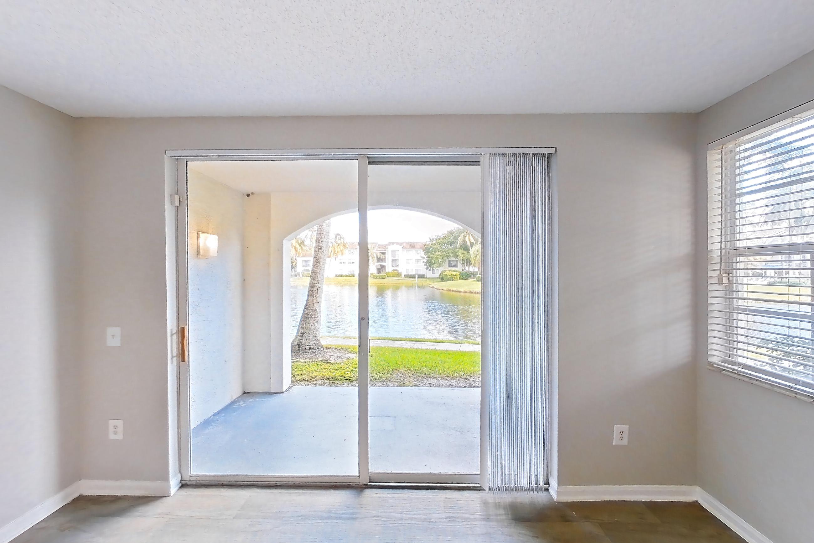 Living room with dark wood-finish flooring and water view, Apartment 06-108 at Miramar Lakes
