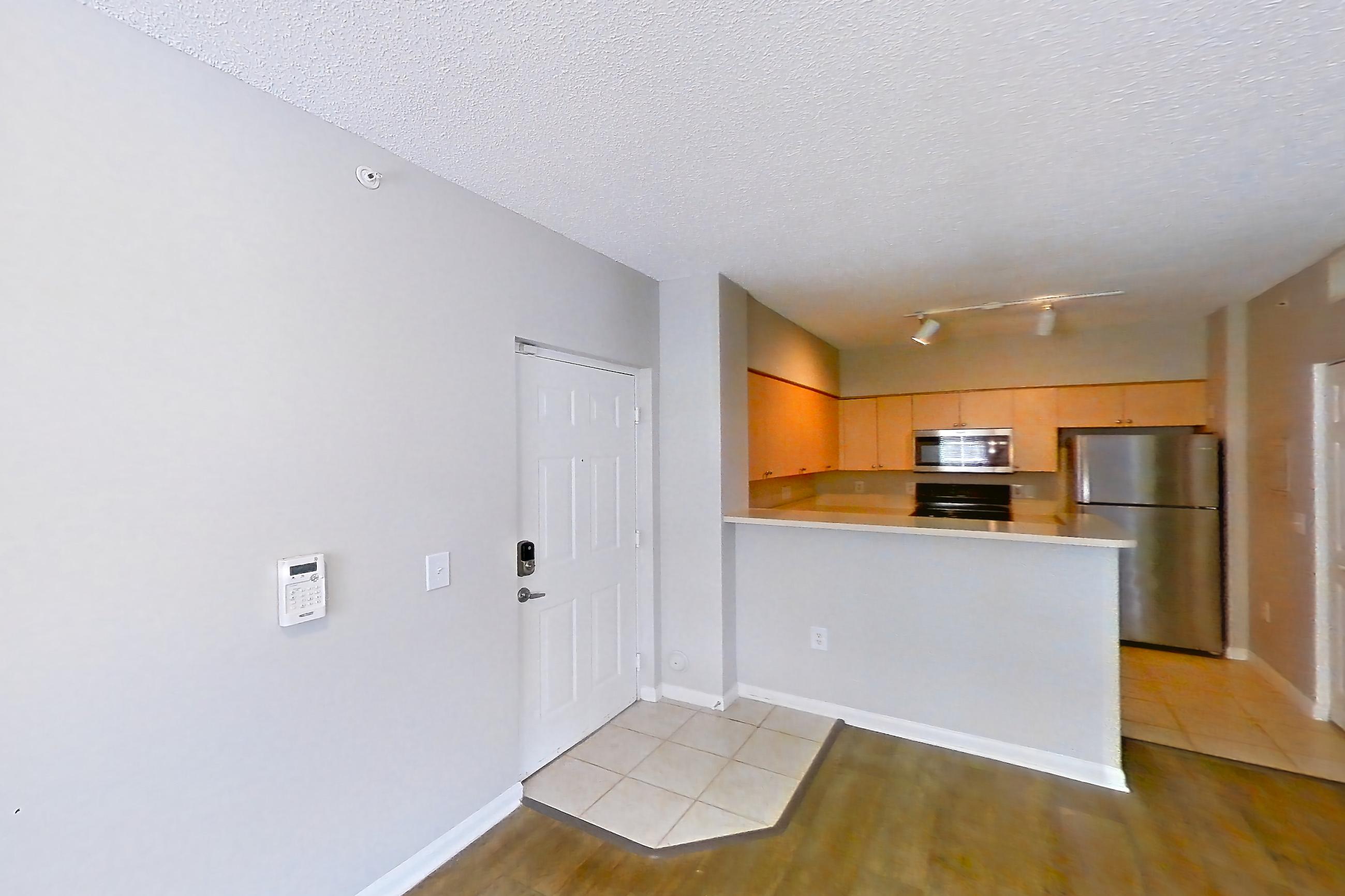 Living space with black appliances, dark wood-finish flooring, light wood-finish flooring, oven/range, refrigerator, and stainless steel appliances, Apartment 06-108 at Miramar Lakes