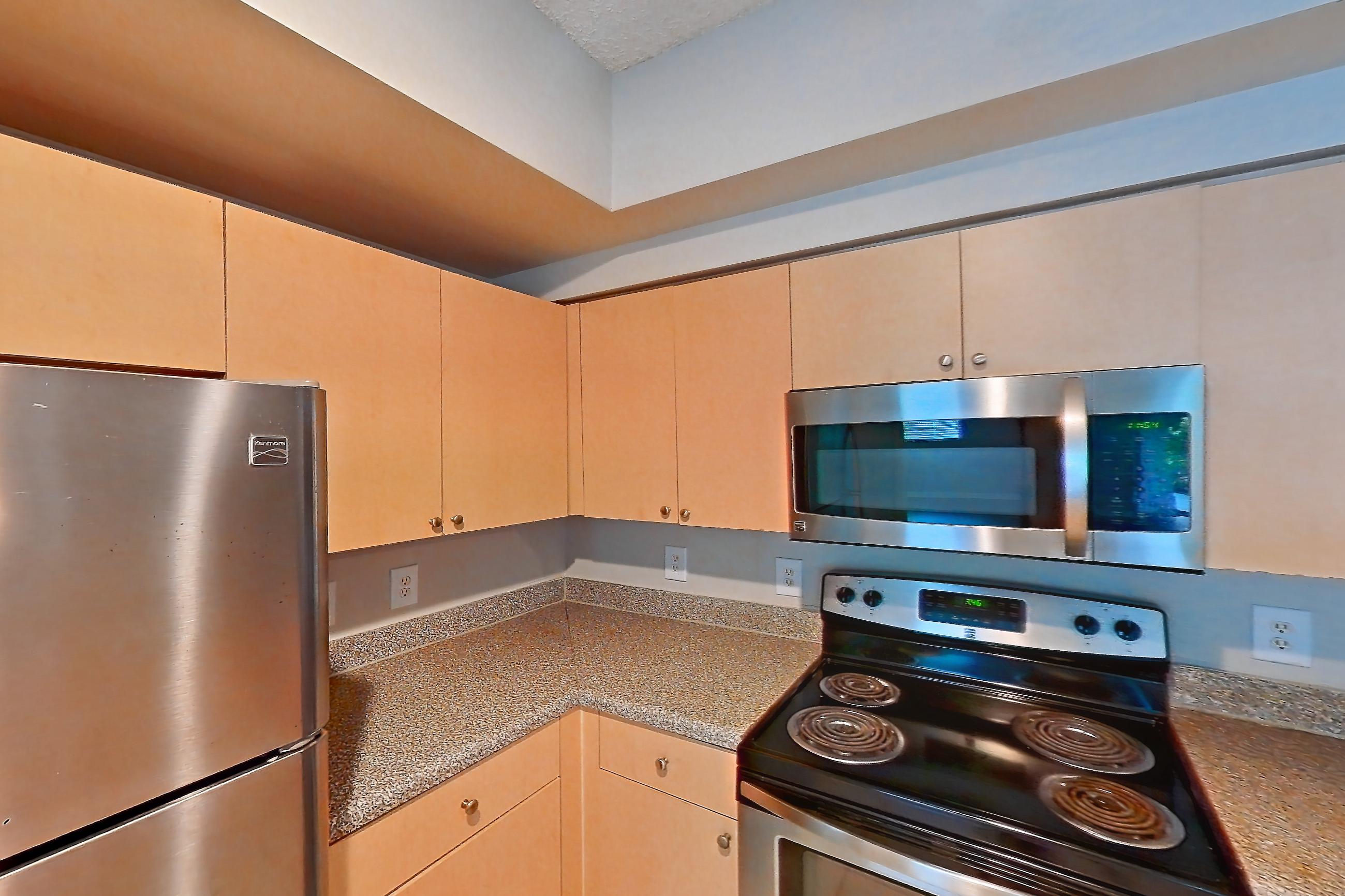 Kitchen with dishwasher, electric range, light countertops, light tile flooring, microwave, oven/range, and stainless steel appliances, Apartment 10-105 at Miramar Lakes