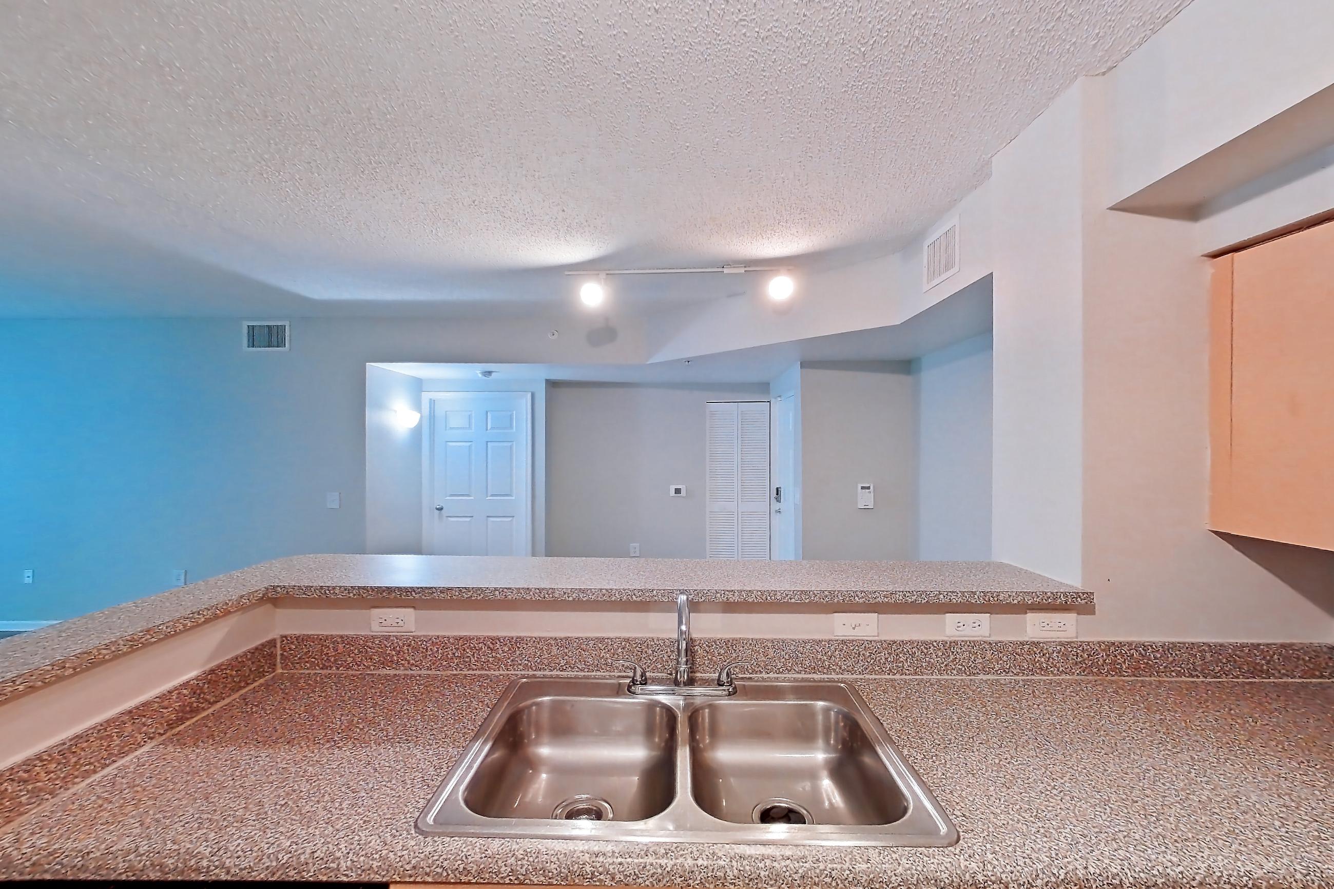 Kitchen with dishwasher, electric range, light countertops, light tile flooring, microwave, oven/range, and stainless steel appliances, Apartment 10-106 at Miramar Lakes