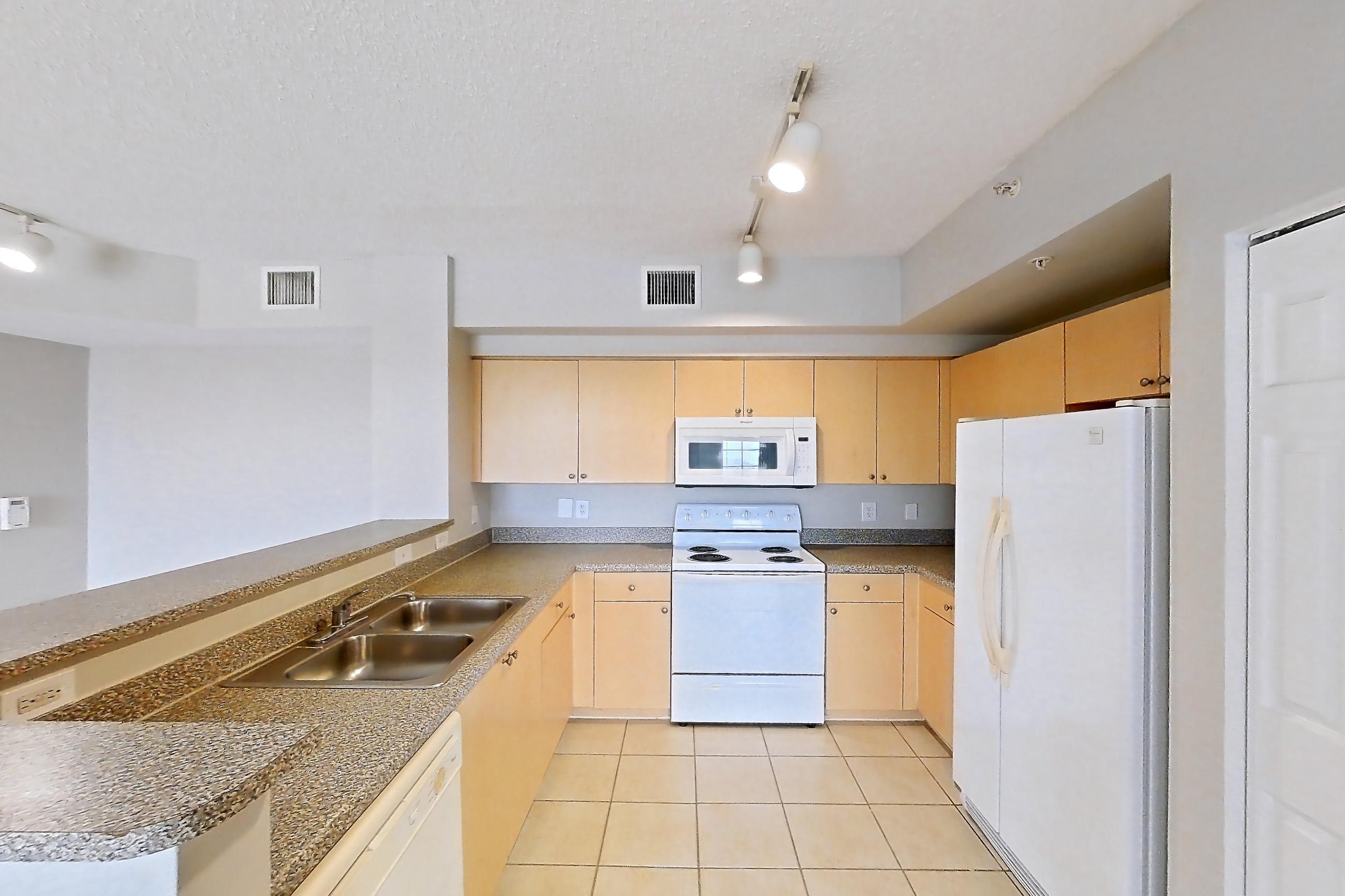 Kitchen entryway with dark countertops, dishwasher, electric range, light tile flooring, light wood-finish flooring, oven/range, refrigerator, and white appliances, Apartment 13-206 at Miramar Lakes
