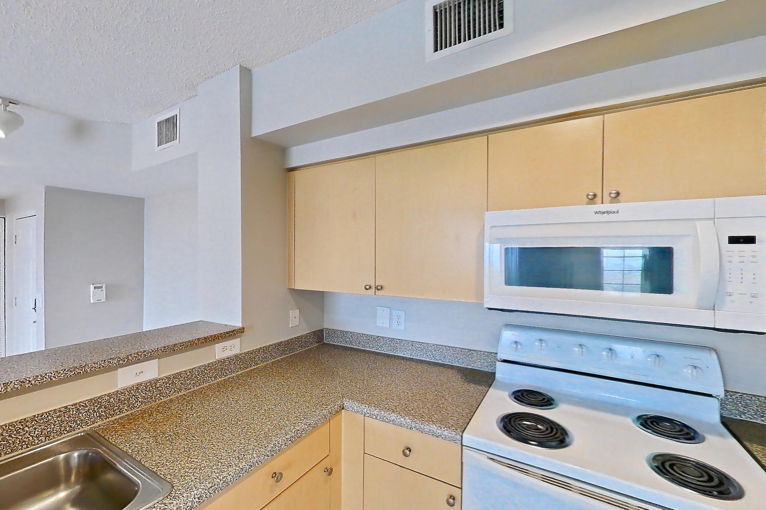 Kitchen with dark countertops, dishwasher, electric range, light tile flooring, microwave, oven/range, and white appliances, Apartment 13-206 at Miramar Lakes