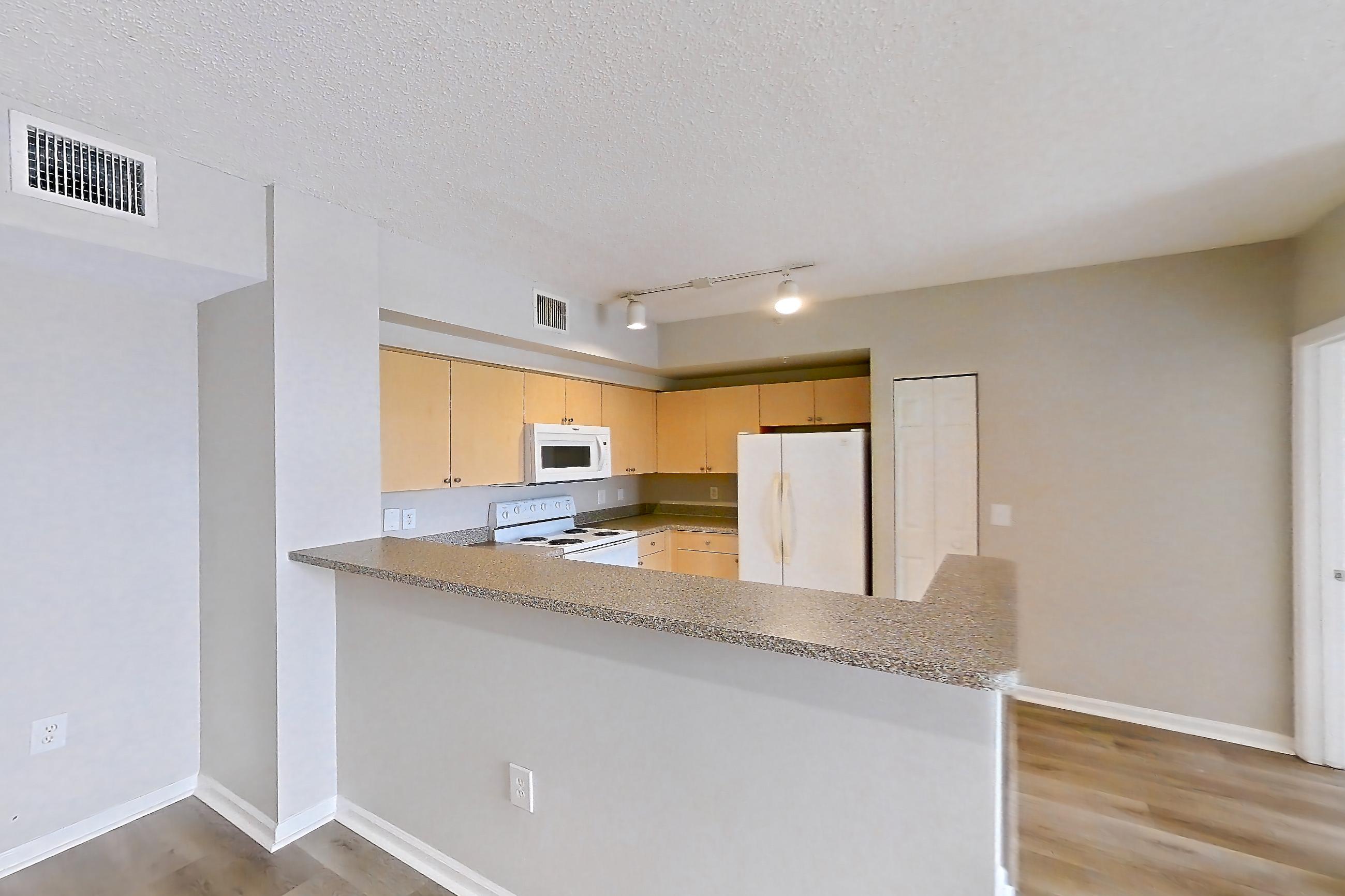 Living space with electric range, light countertops, light wood-finish flooring, oven/range, refrigerator, and white appliances, Apartment 13-206 at Miramar Lakes