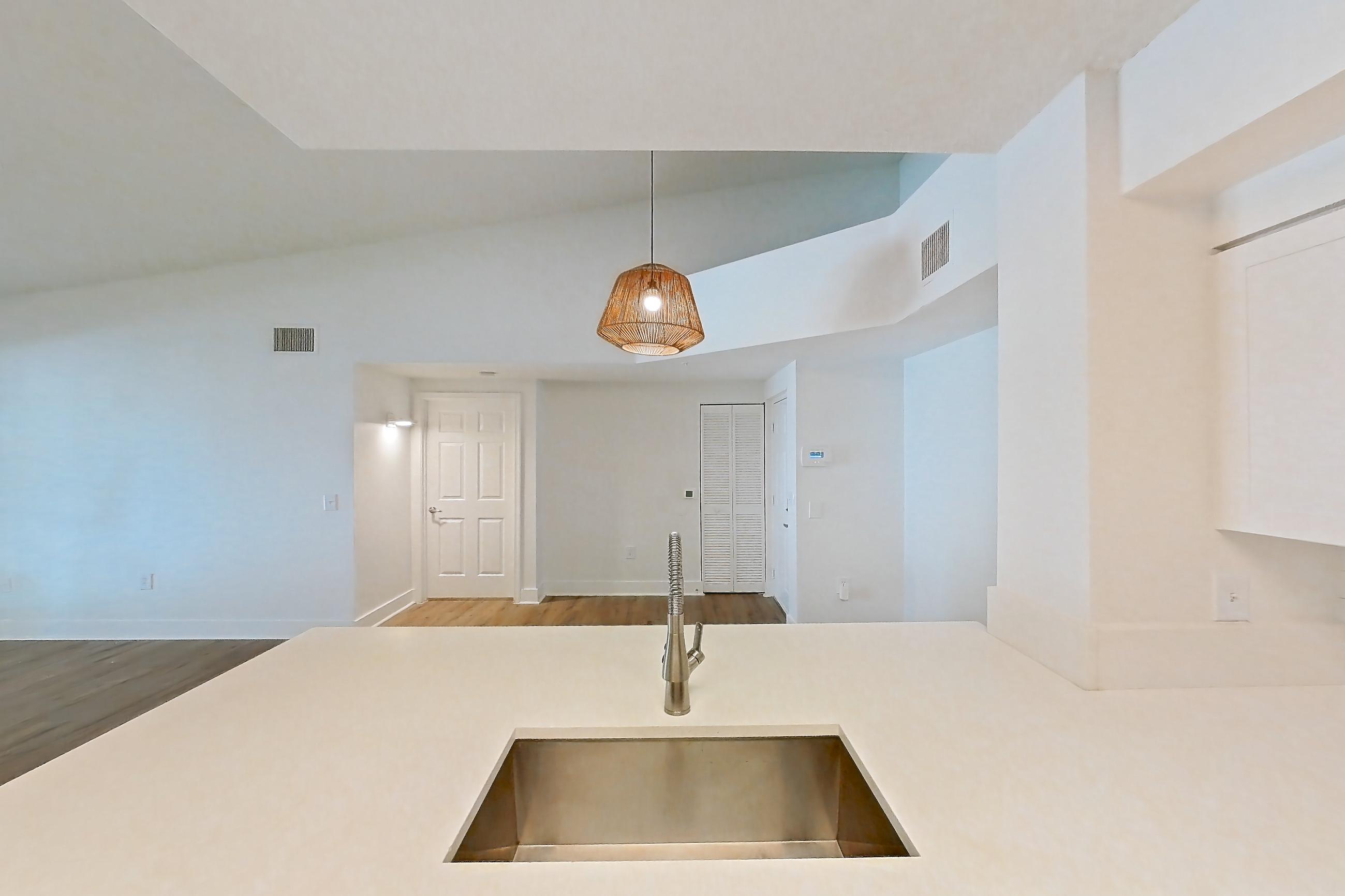 Kitchen with dishwasher, electric range, light countertops, light stone countertops, light wood-finish flooring, microwave, oven/range, and stainless steel appliances, Apartment 01-208 at Miramar Lakes